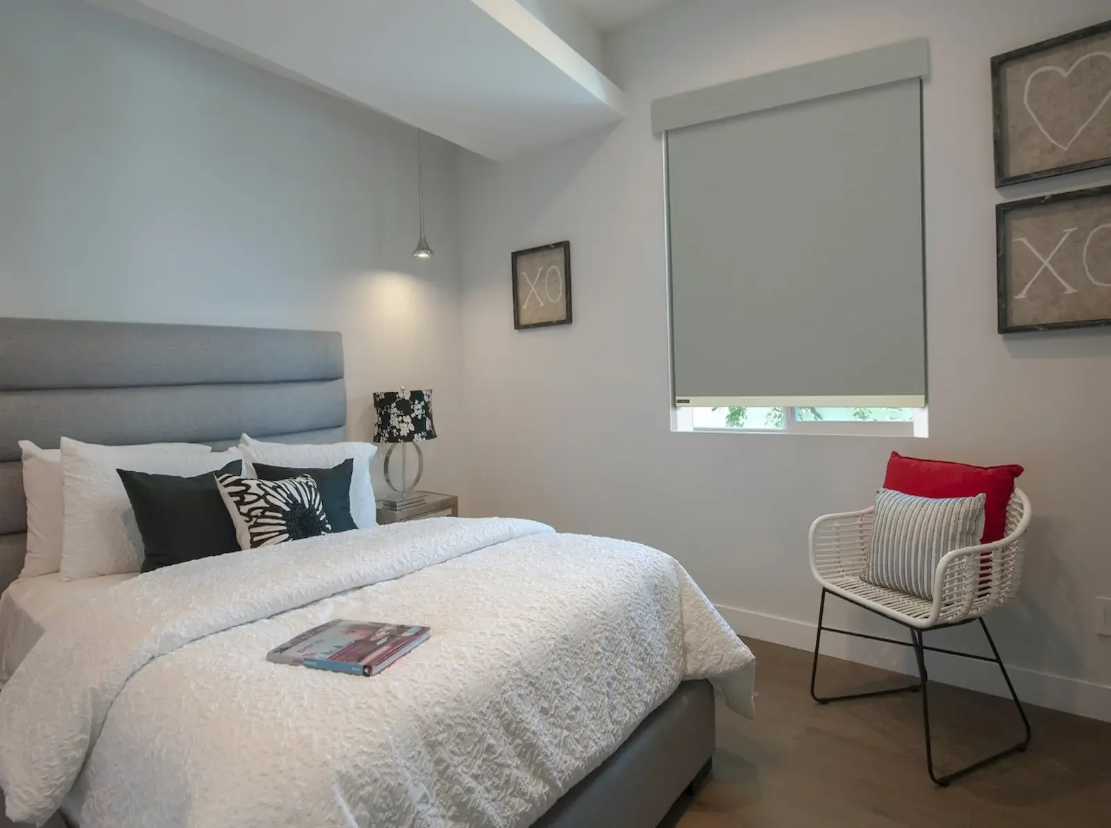 Motorized blackout roller shades mostly lowered in a primary bedroom for complete light control