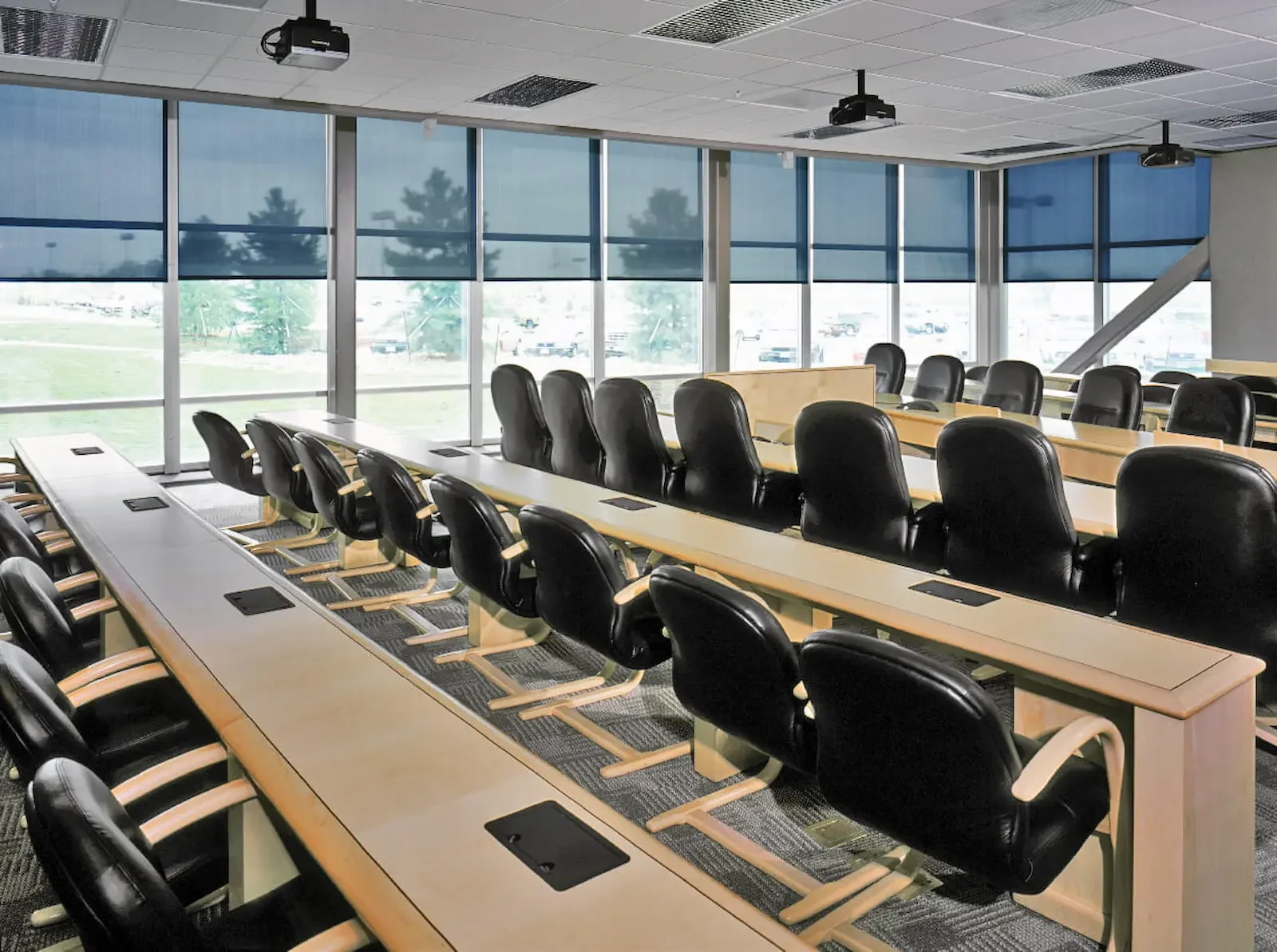 Large solar roller shades covering a wall of classroom windows