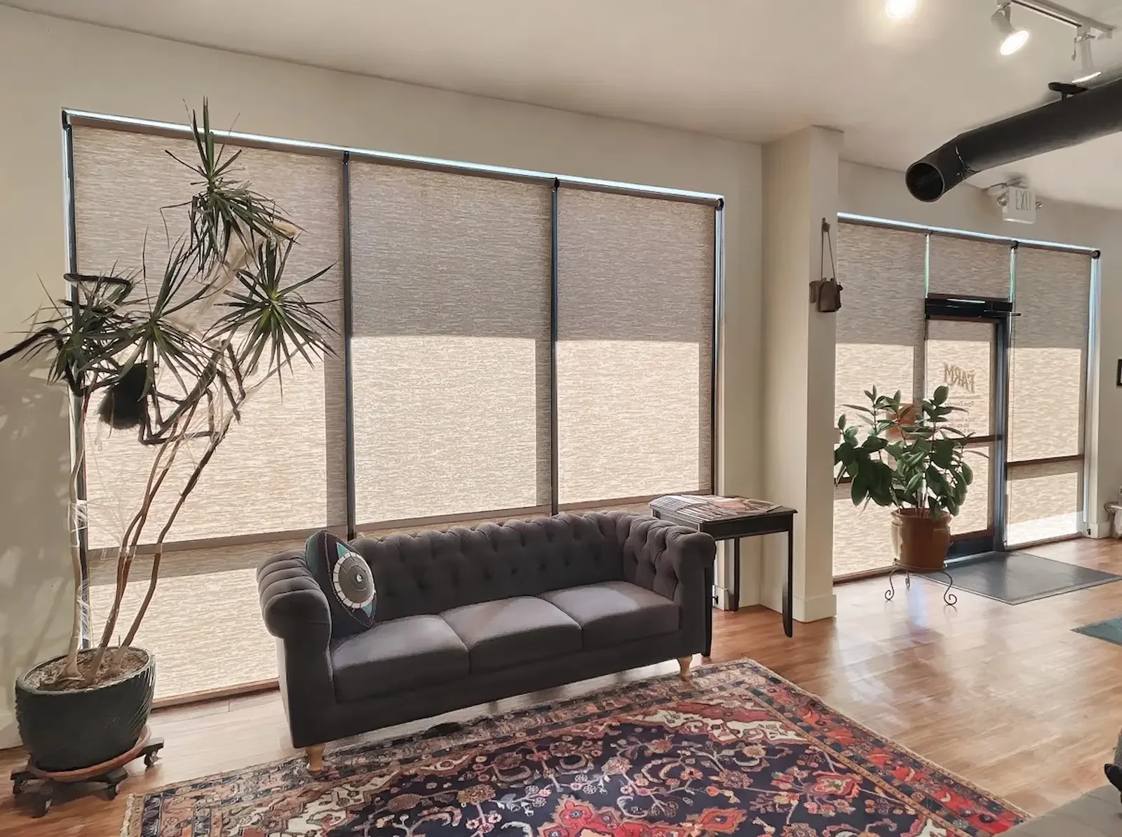 Roller shades covering floor-to-ceiling windows in an office lobby