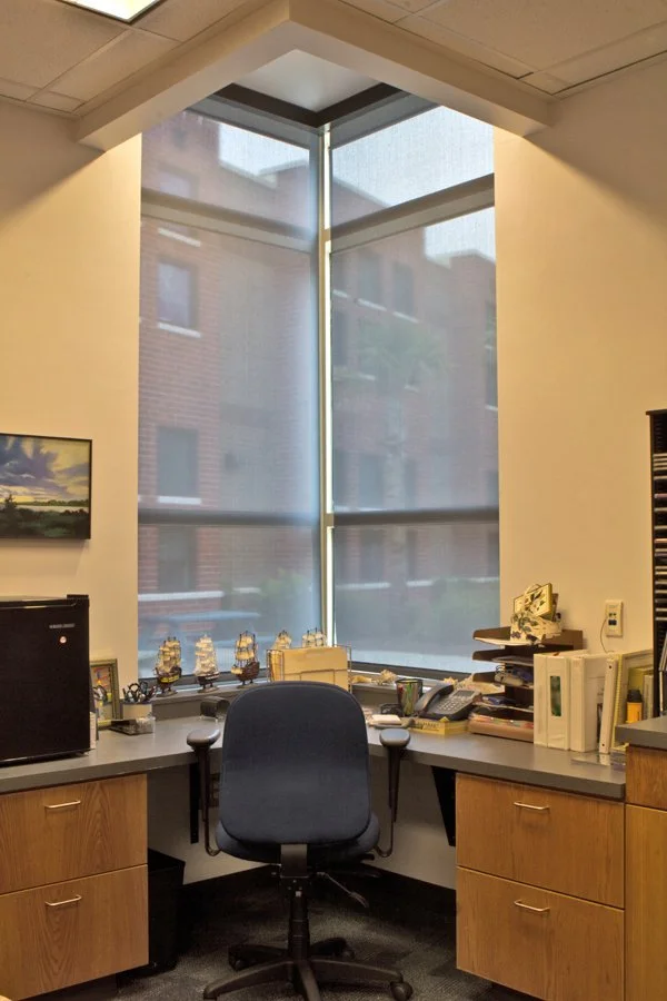 Tall commercial solar shades controlling light in a corner office