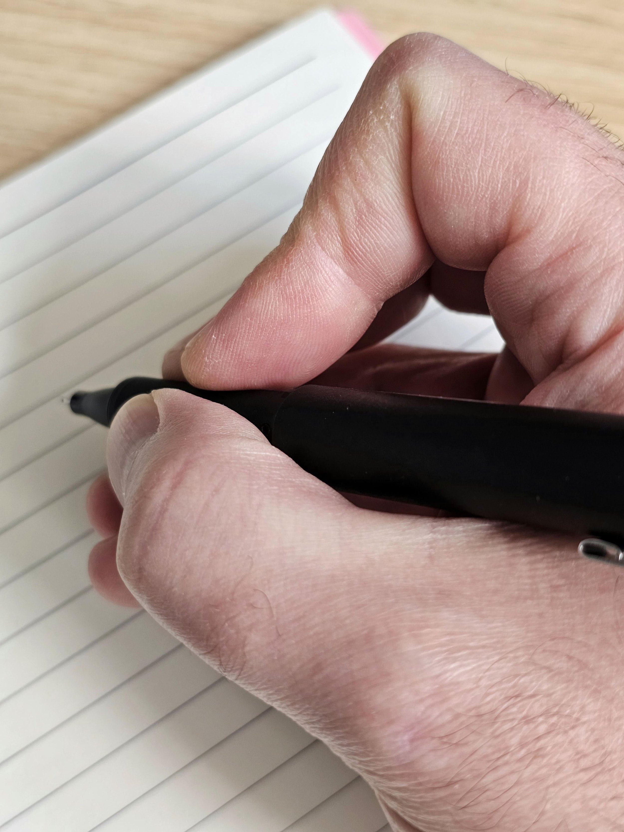 Une main d'homme écrit avec un feutre sur un carnet