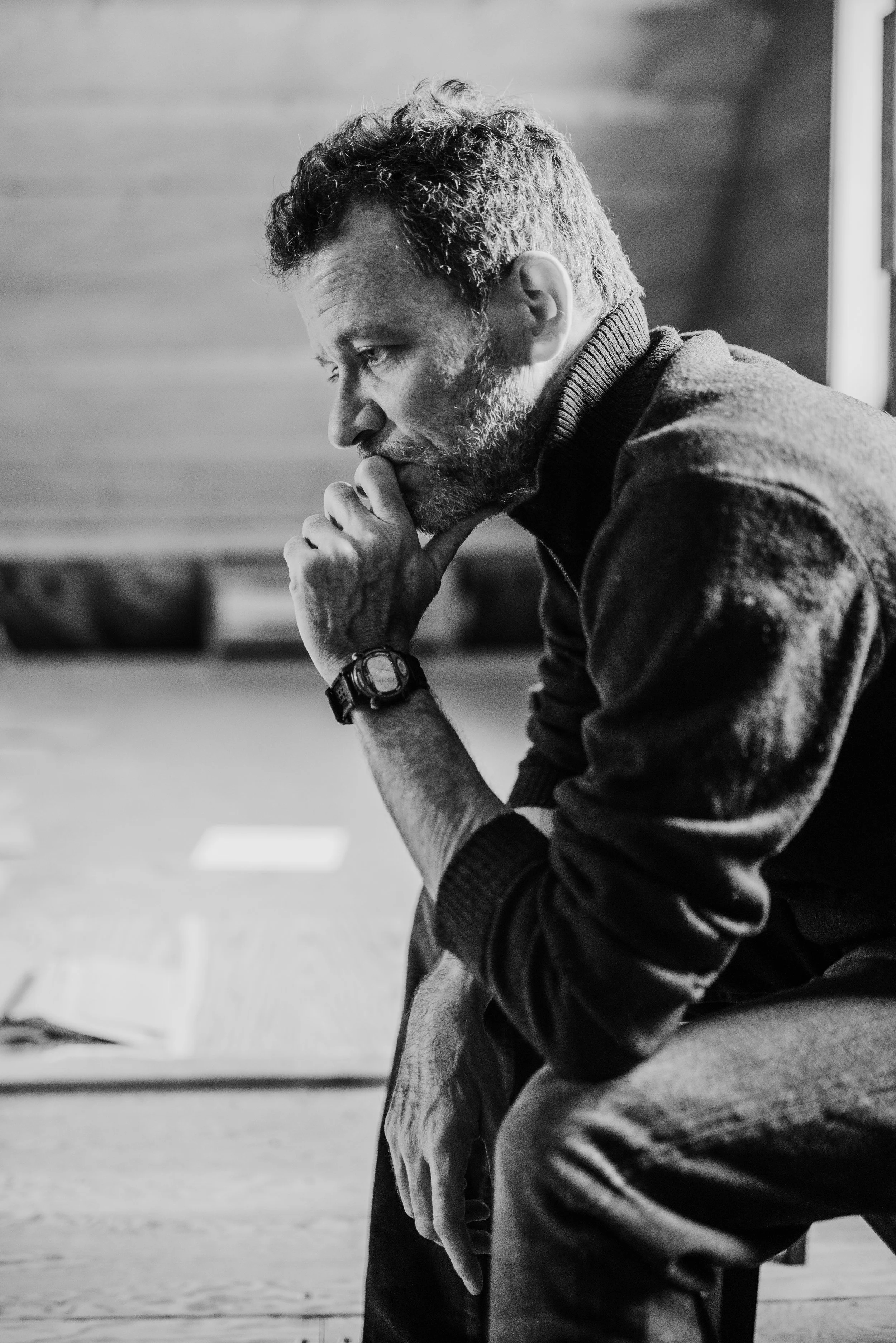 Yann Martel in black and white portrait, seated and looking down thoughtfully