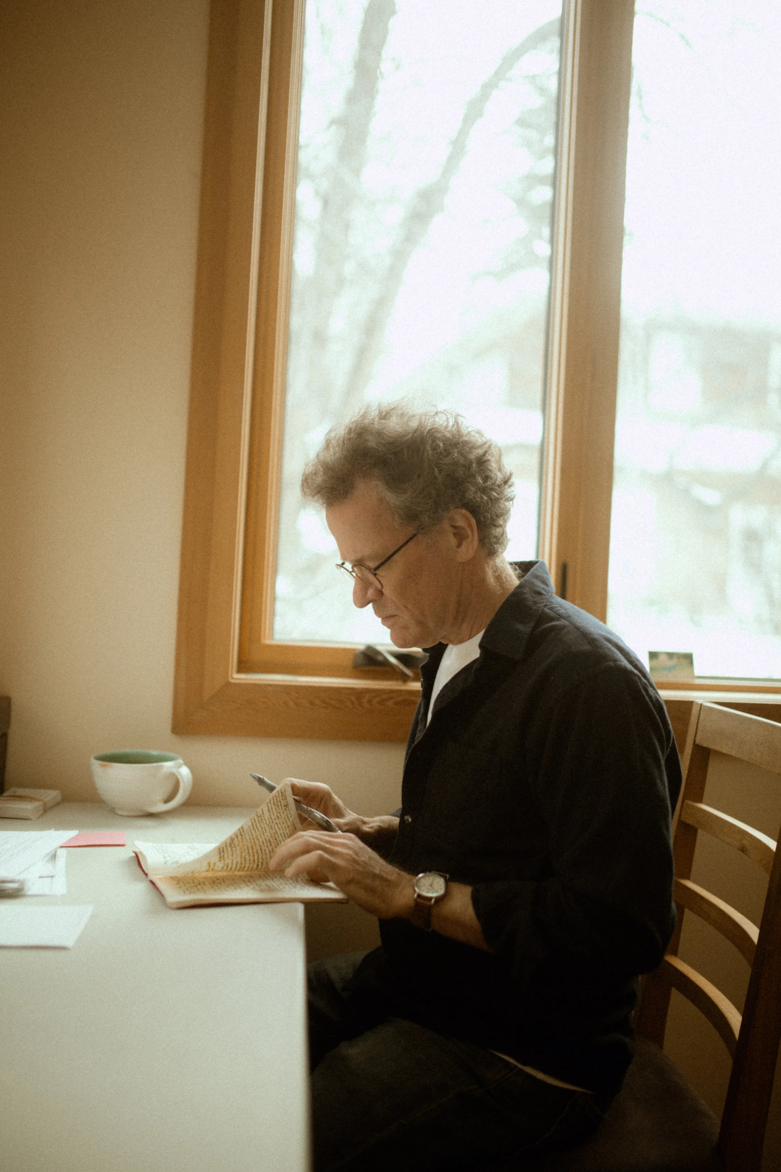 Yann Martel side view flipping through a notebook at a desk