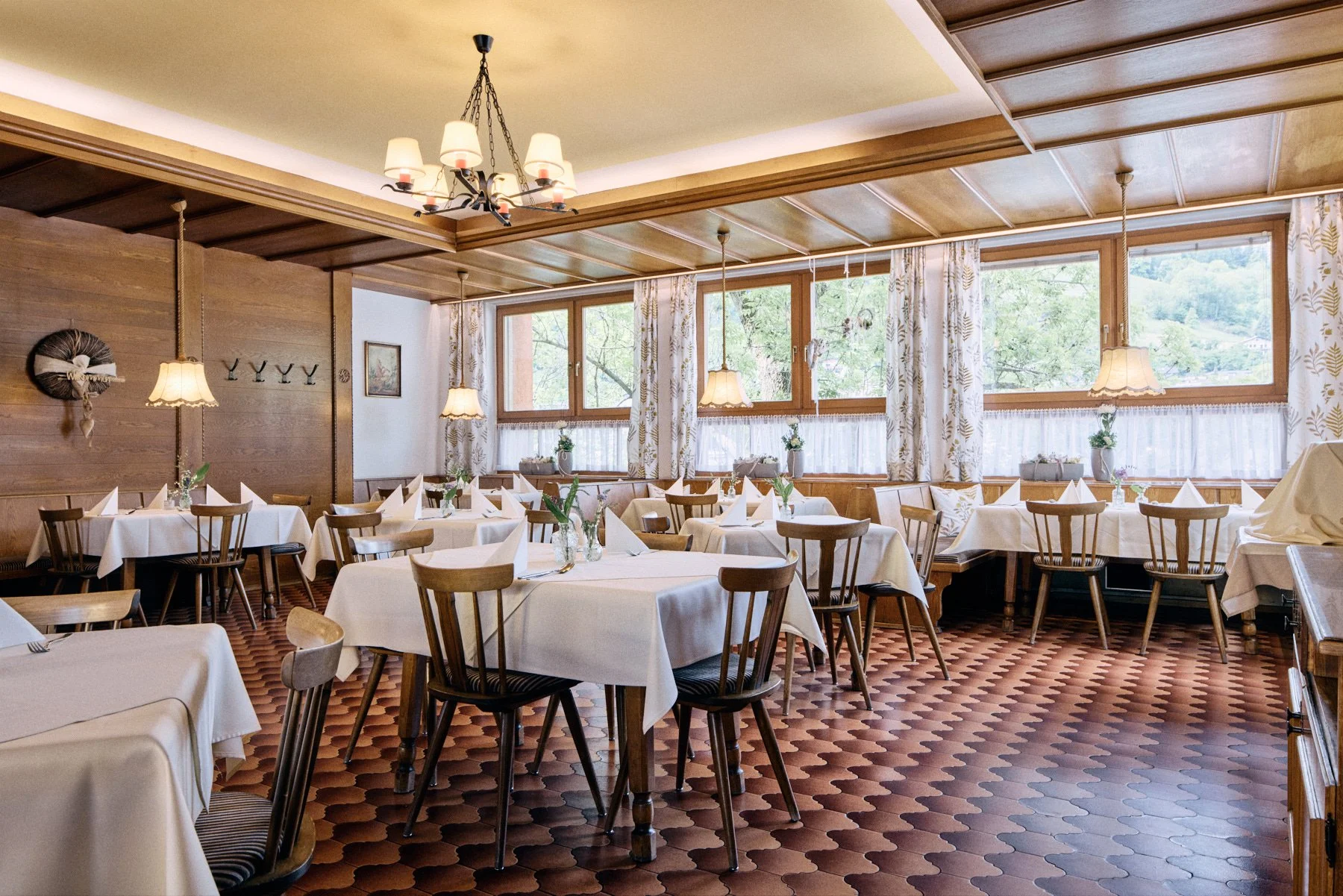 Ein schön gedecktes Restaurant mit weißen Tischdecken, Stühlen und großen Fenstern, die viel Tageslicht hereinlassen.