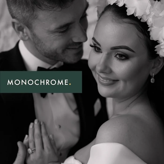 A black and white photo of a smiling bride and groom, with the bride wearing a floral headpiece and the groom in a tuxedo, with a green banner that says "Monochrome."