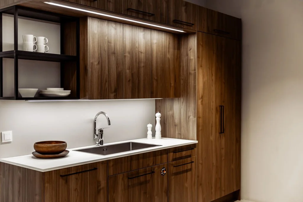 Keittö, jossa on ruskeat puuräät, valkoinen taso ja metallinen hana.