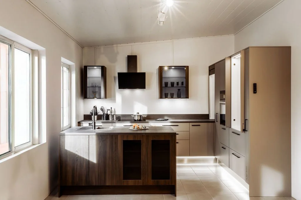 Keittiö, moderni, puiset ja vaaleat kaapit, suuri ikkuna, valkoinen seinä, keittiöallas ja keittotaso, seinäkaapit, tulostin, keittiövälineitä