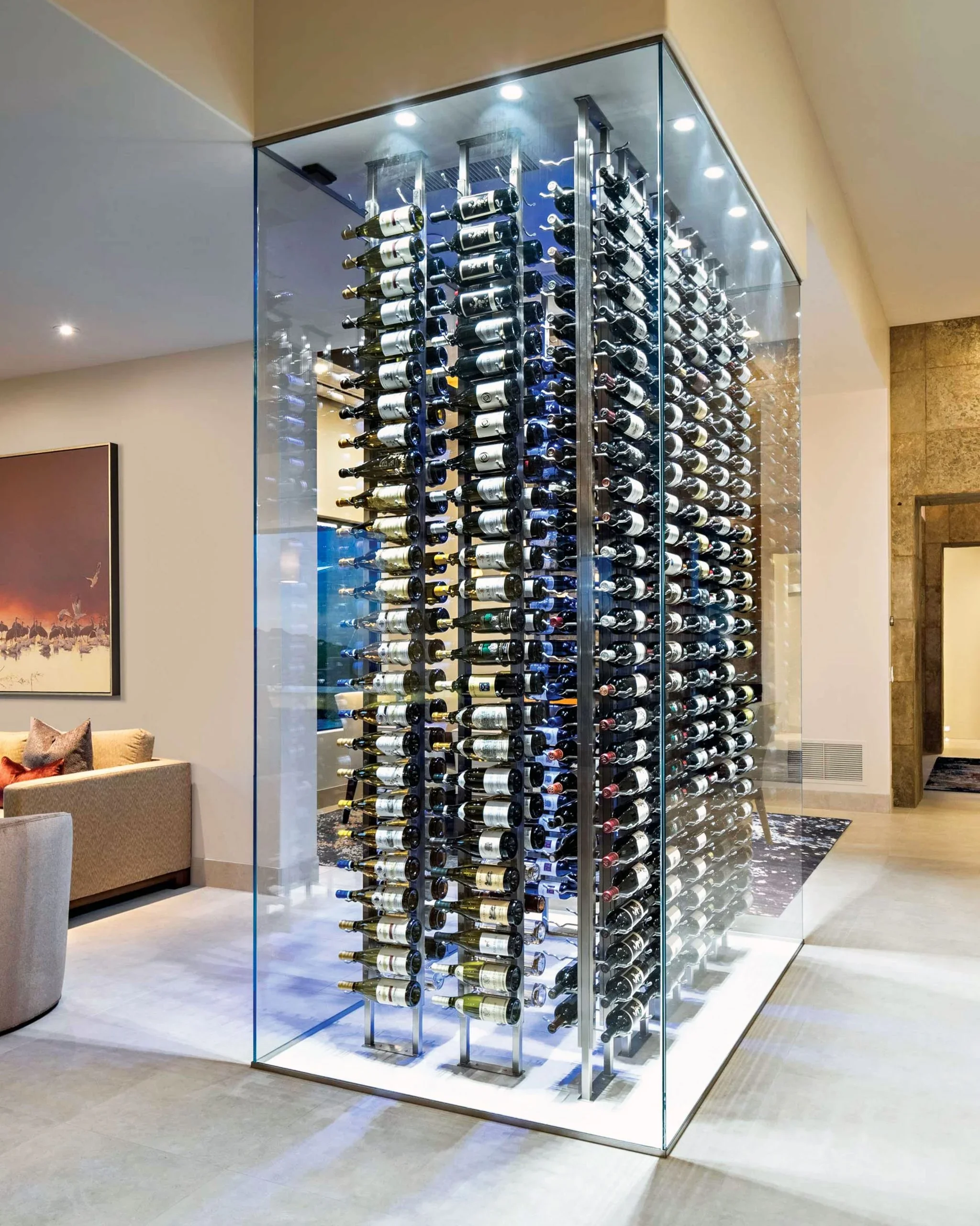 A glass-encased wine rack with multiple bottles of wine displayed horizontally in a modern indoor setting.