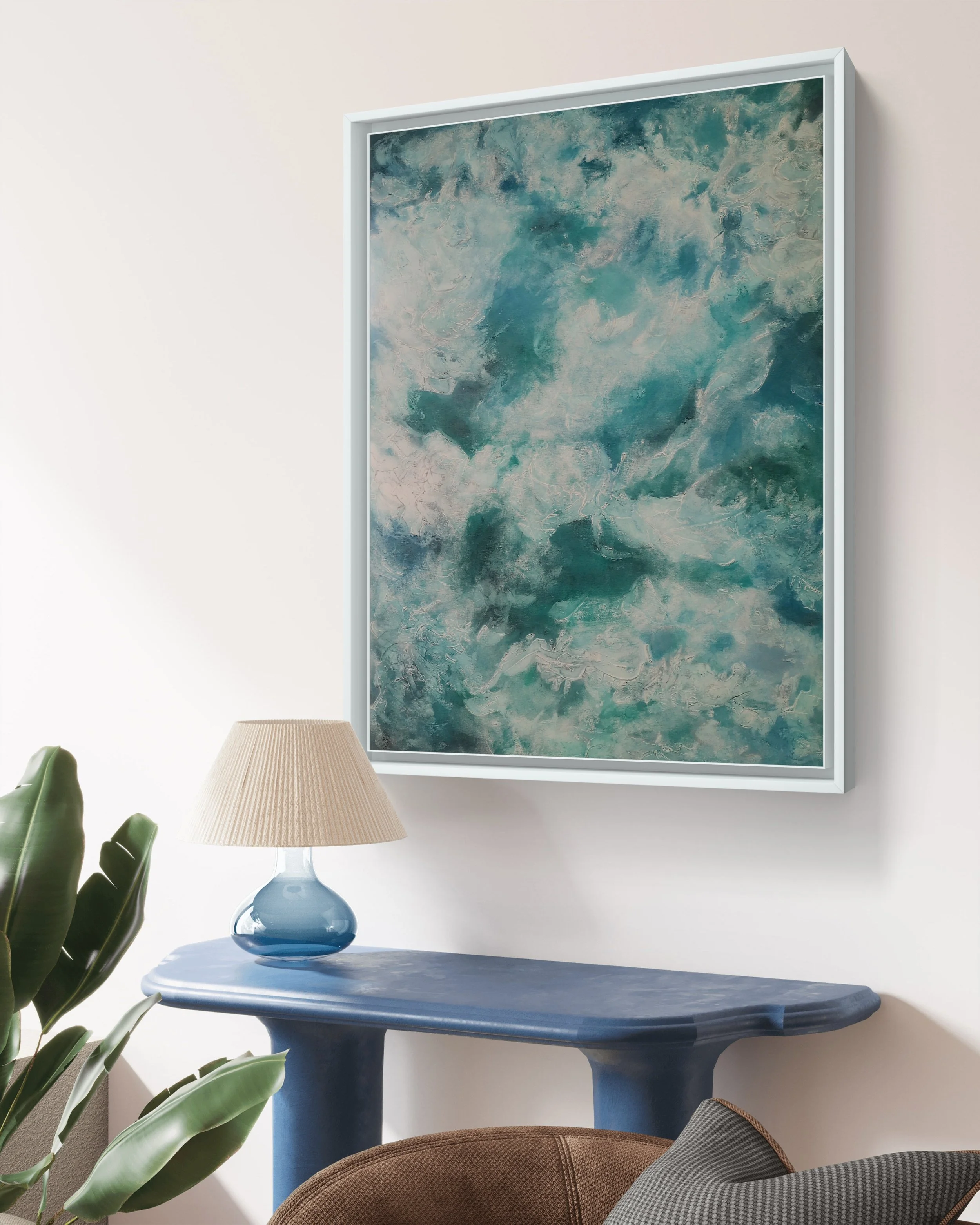 A room decor scene with a large abstract painting in blue tones hanging on the wall, a blue table below it, a blue glass table lamp, a green plant on the side, a brown chair, and a gray cushion.