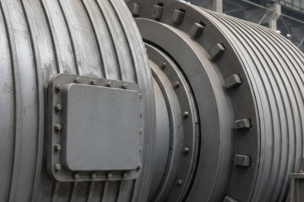 Close-up of a large industrial turbine or engine component with metallic cylindrical parts and a rectangular access panel.