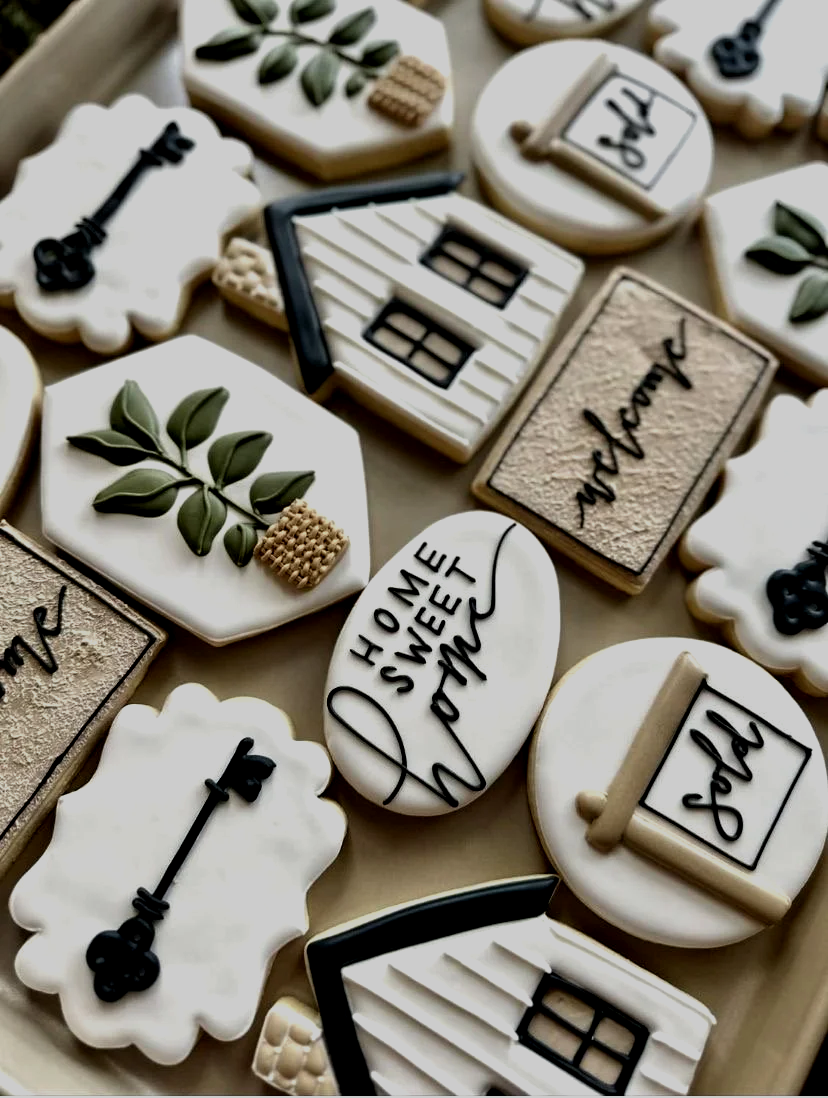 Collection of decorative cookies with home, love, and house themes, decorated with icing and fondant in white, black, and beige colors.