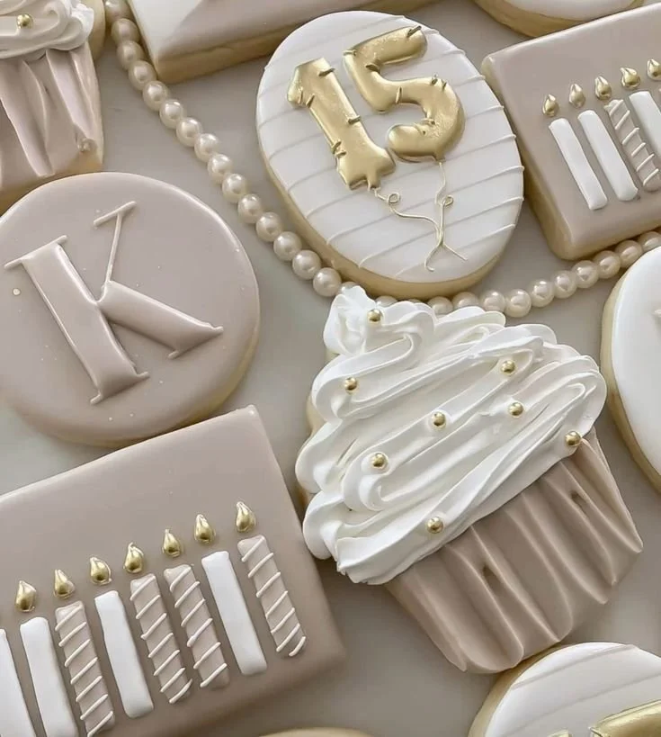 Decorated cookies for a 15th birthday celebration, featuring a cupcake, candles, balloons, and the number 15 in gold.