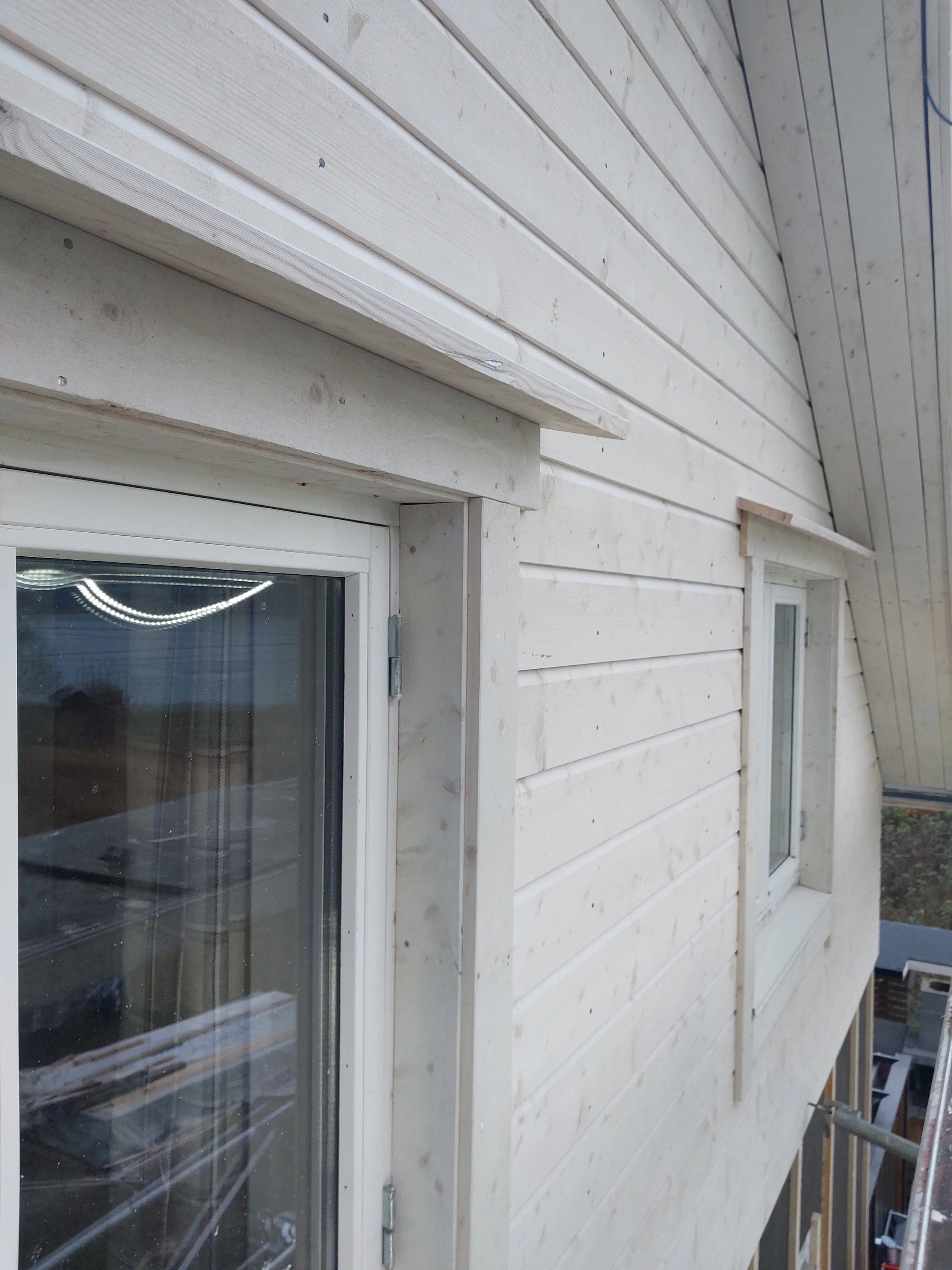 Ny fassade: hvitt hus med liggende trepaneler og to vinduer