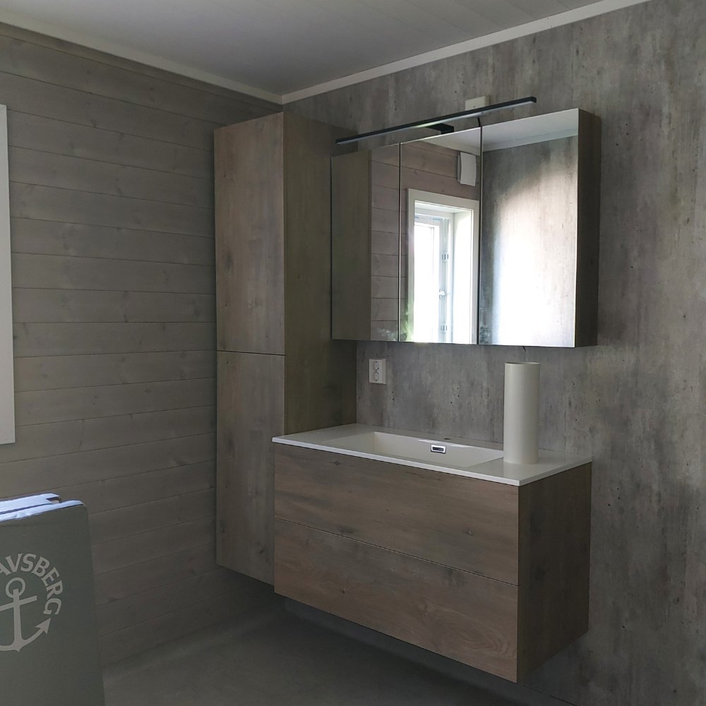 Lekker bademiljø med en stor, moderne speilskap over vasken, og en liten vindu som slipper inn lys.