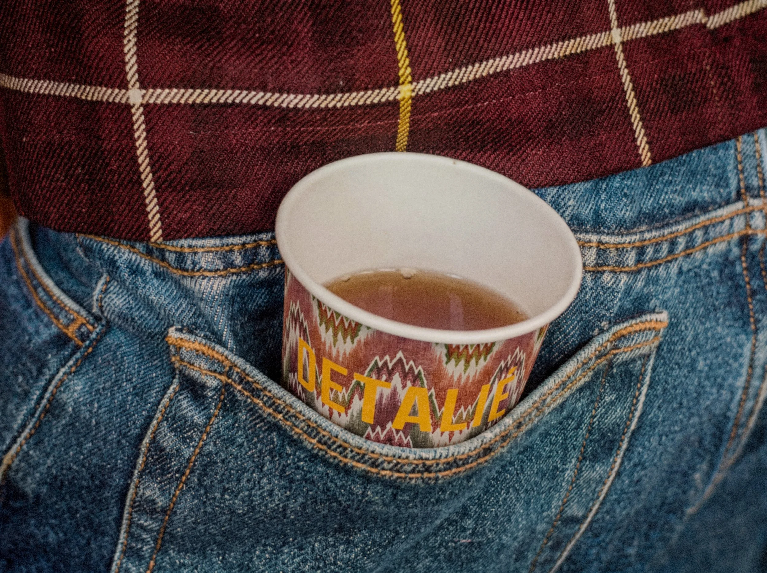 DETALIÉ to-go kop med ikat-mønster i baglommen på et par jeans - kaffe fra boutique café i Holbæk