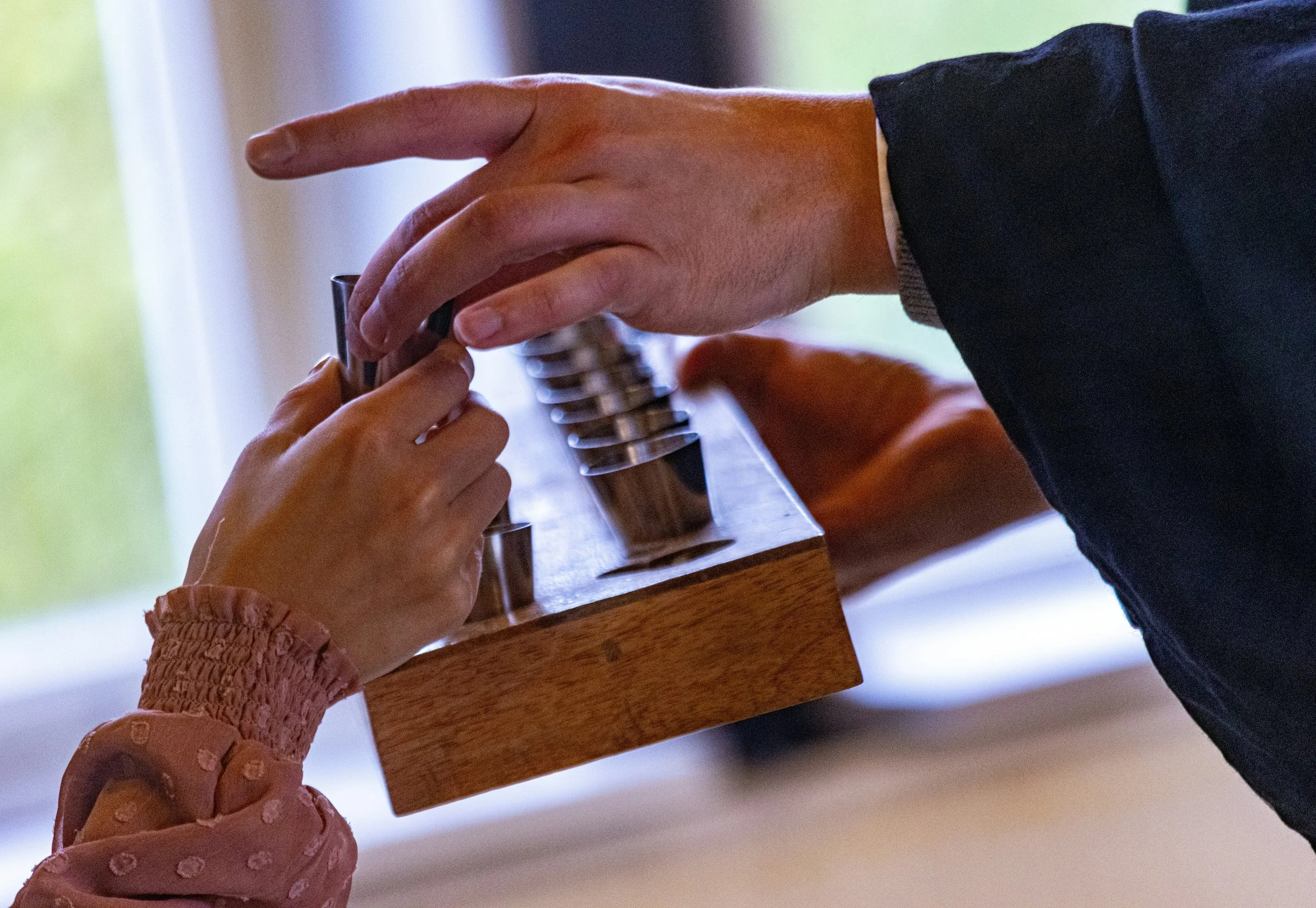 An adult handing communion cup into a younger persons hand.
