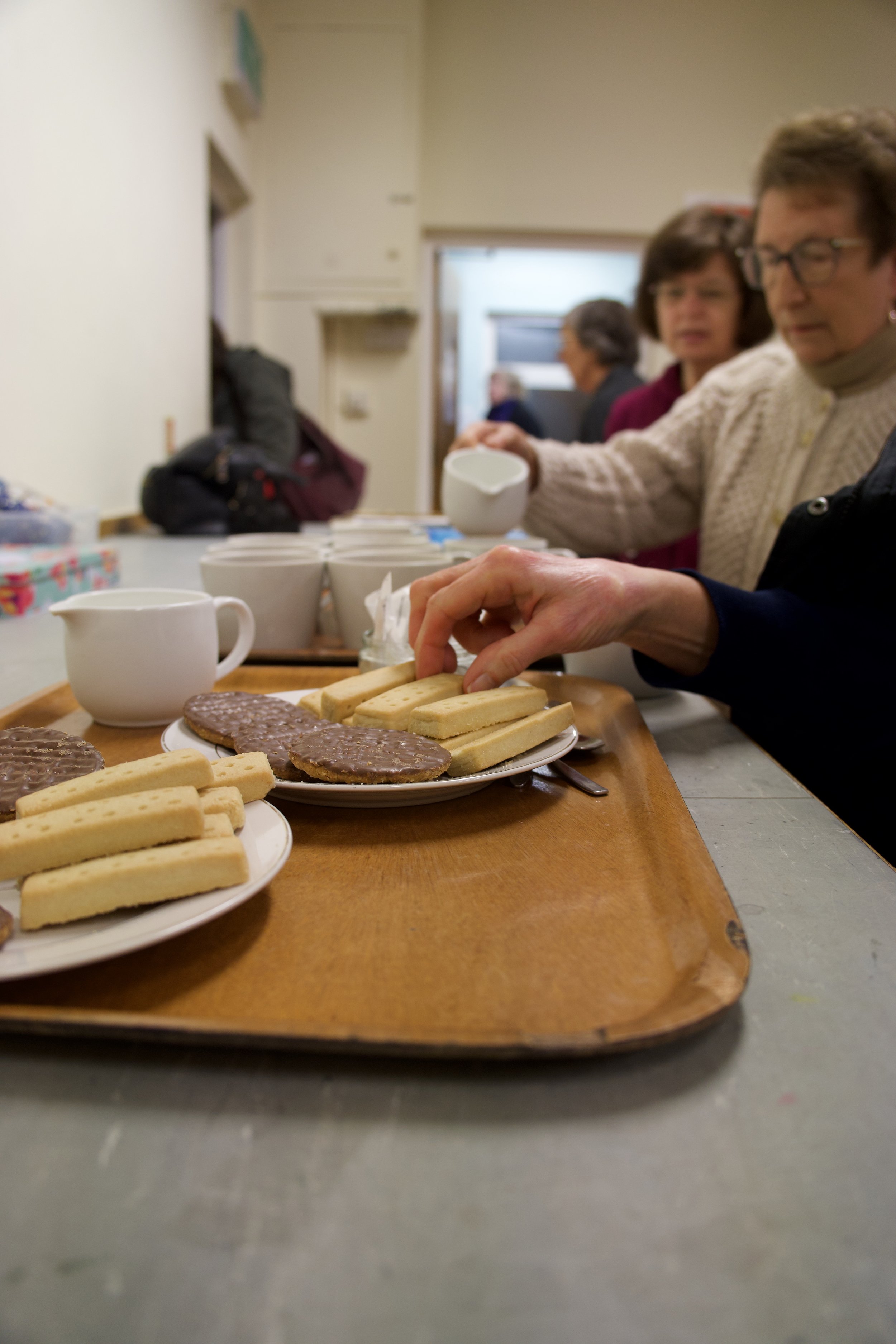 People serving and preparing cookies on a tray at a community event or gathering.