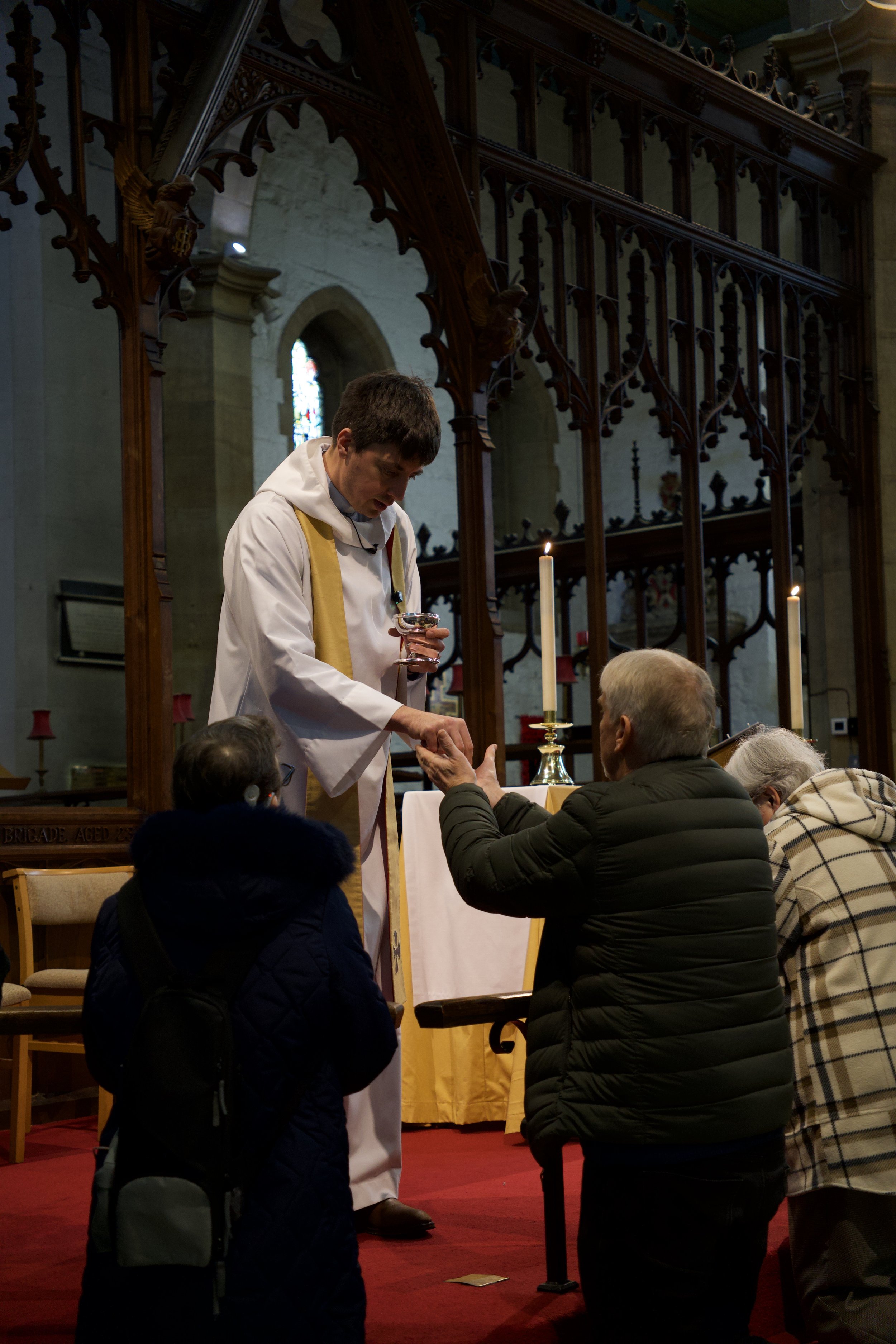 A priest at an altar giving communion to a congregation in a church.