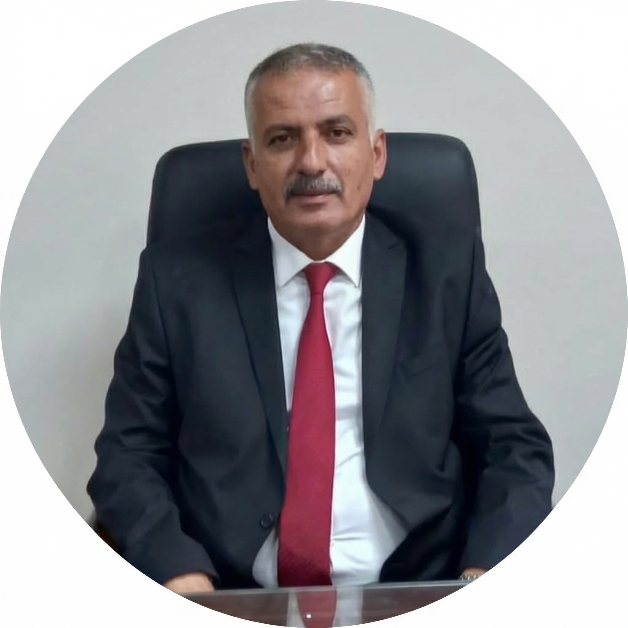 Ofis ortamında, siyah koltukta oturan, resmi kıyafet giymiş, kırmızı kravatlı, orta yaş erkek