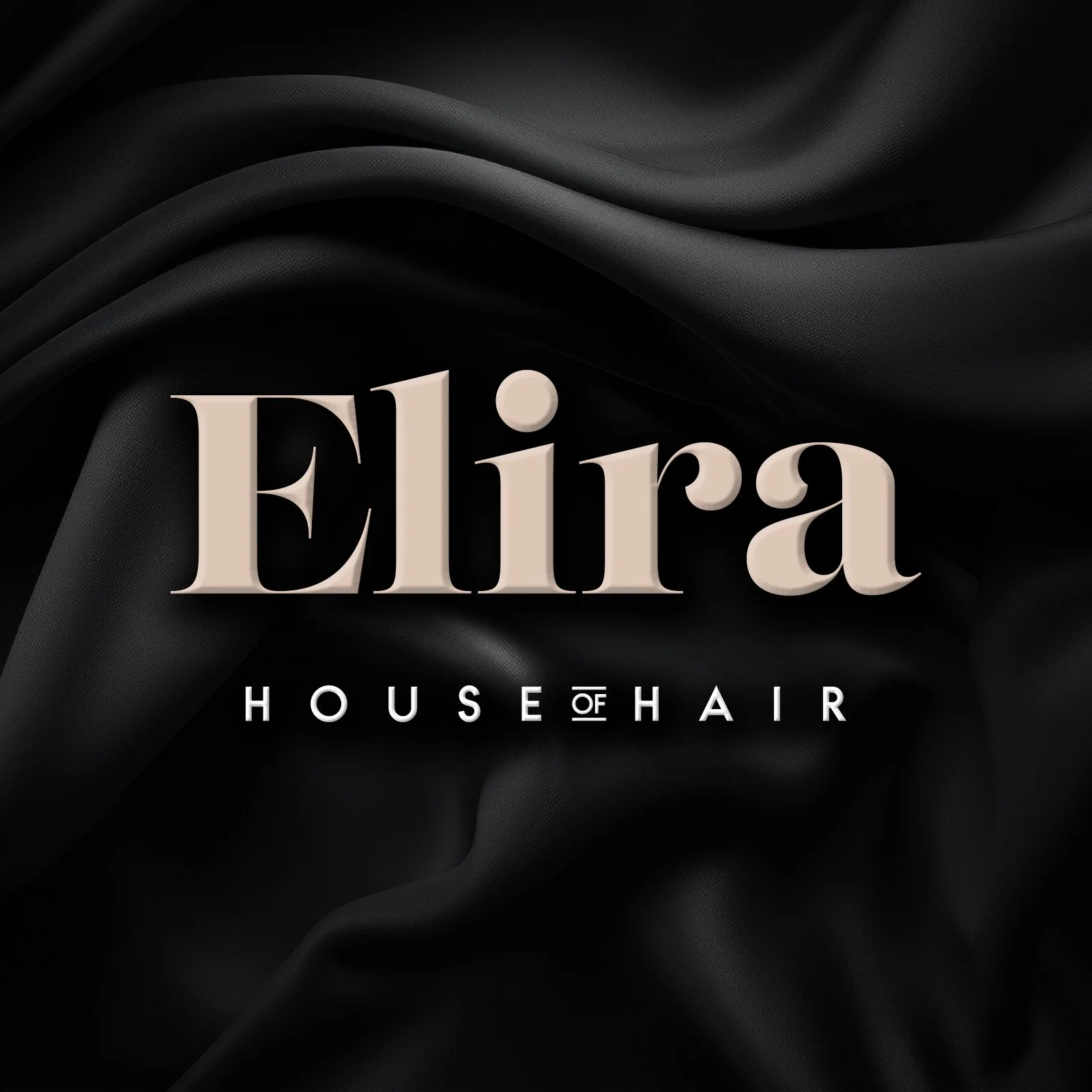 Text on black fabric background reading "Elira HOUSE OF HAIR."