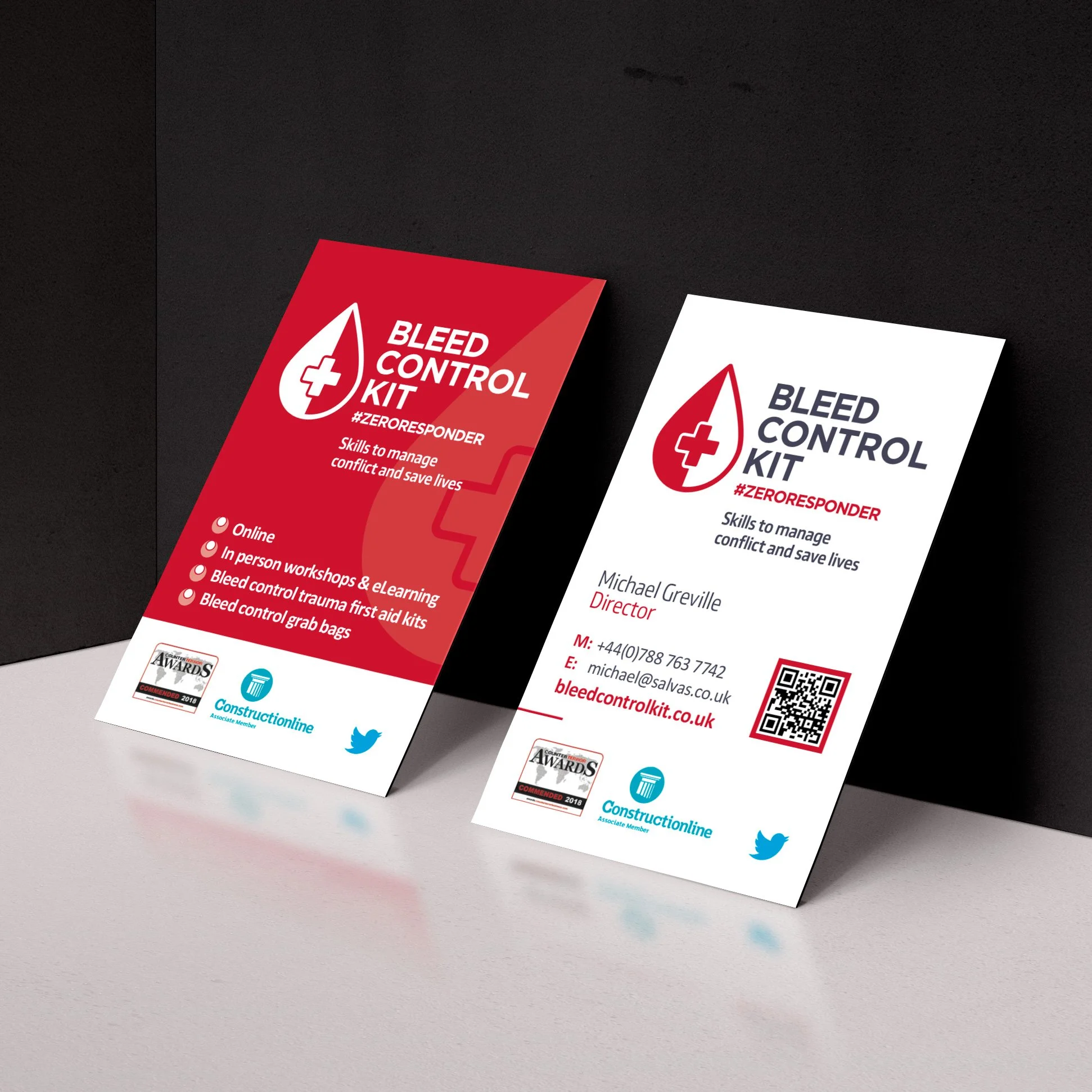 Business cards for Bleed Control Kit, with one red and one white card, featuring a red blood drop with a white cross, contact details, and social media icons.