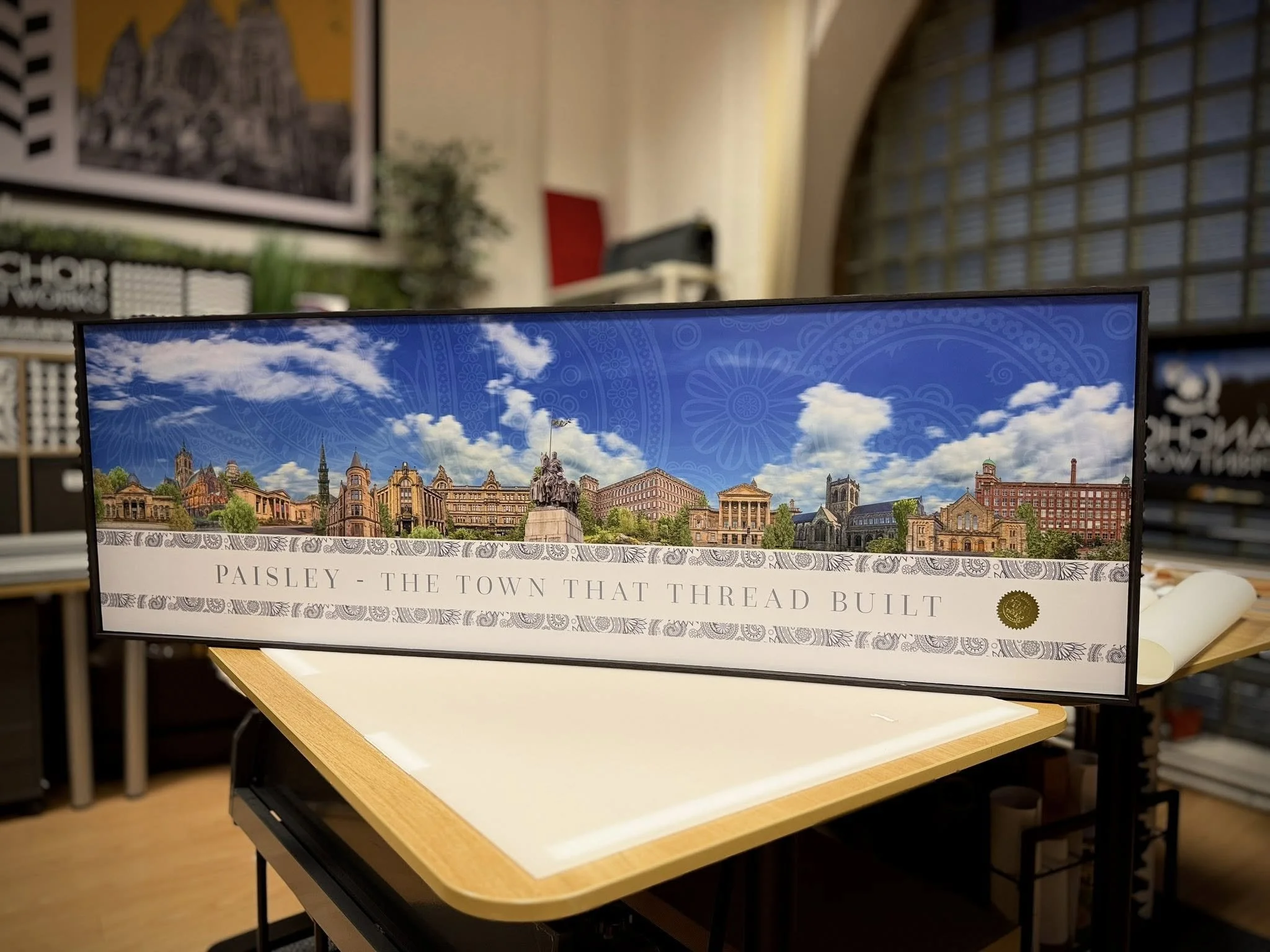 Panoramic banner displaying historic buildings and a cloudy sky, with a banner text that reads 'PAISLEY - THE TOWN THAT THREAD BUILT'.