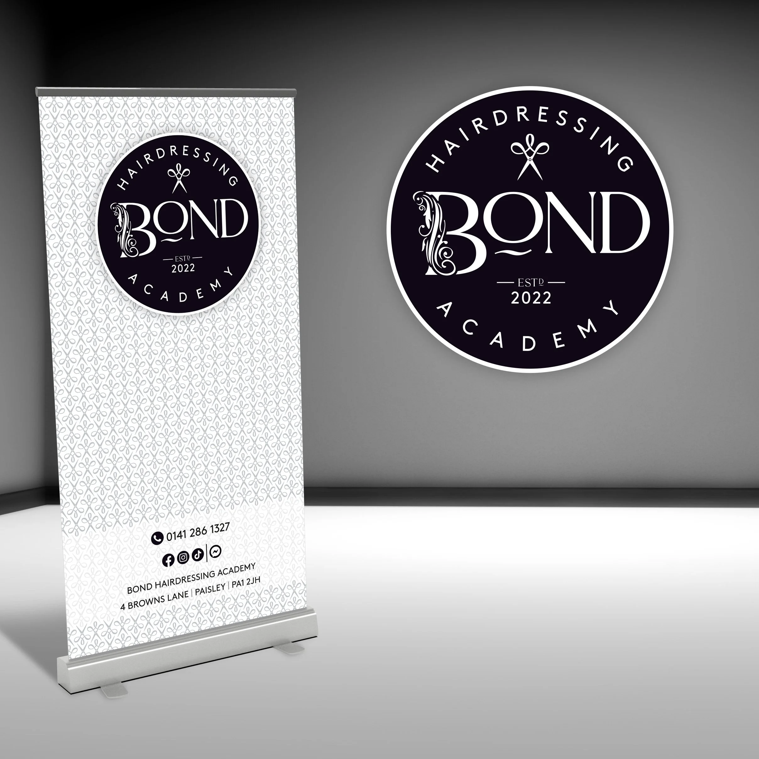 Black circular sign and a white vertical banner both displaying the logo and contact information for Bond Hairdressing Academy, established 2022.