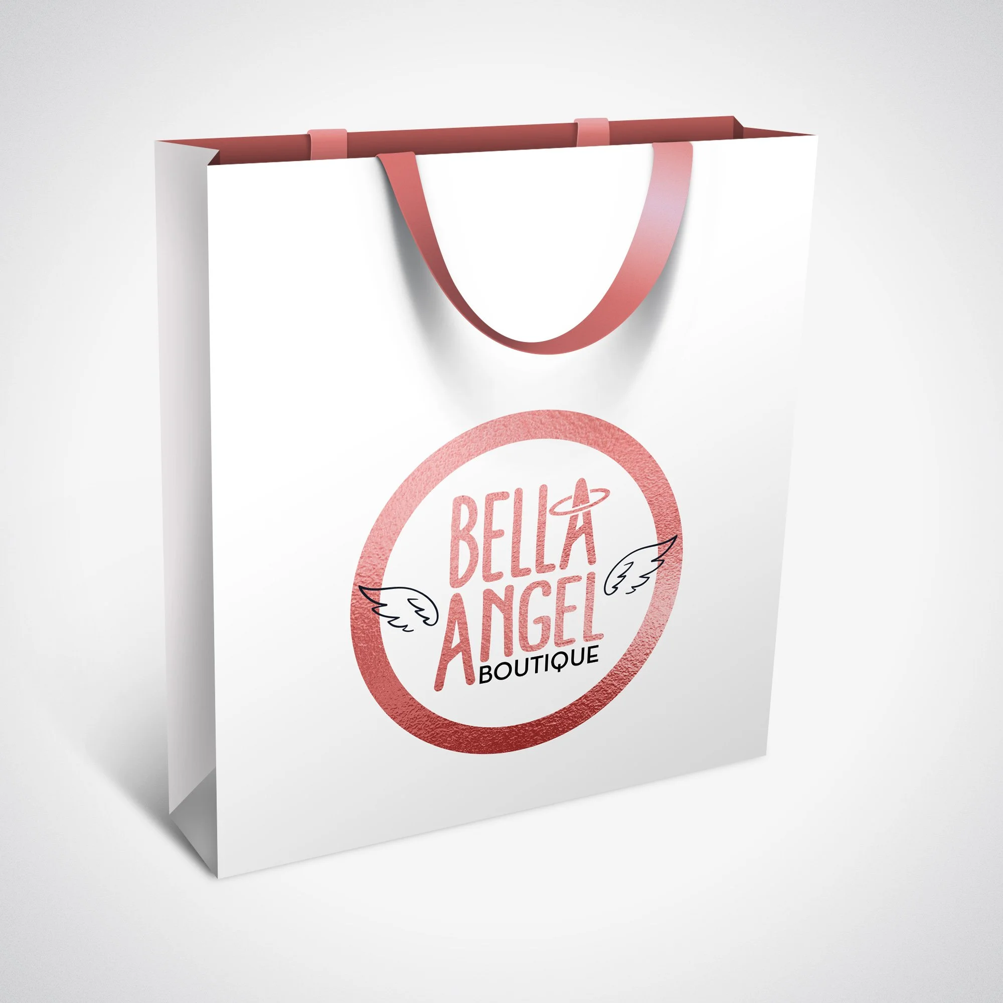 White shopping bag with pink handles and a logo for Bella Angel Boutique, featuring a pink circle, wings, and a small planet with a ring.