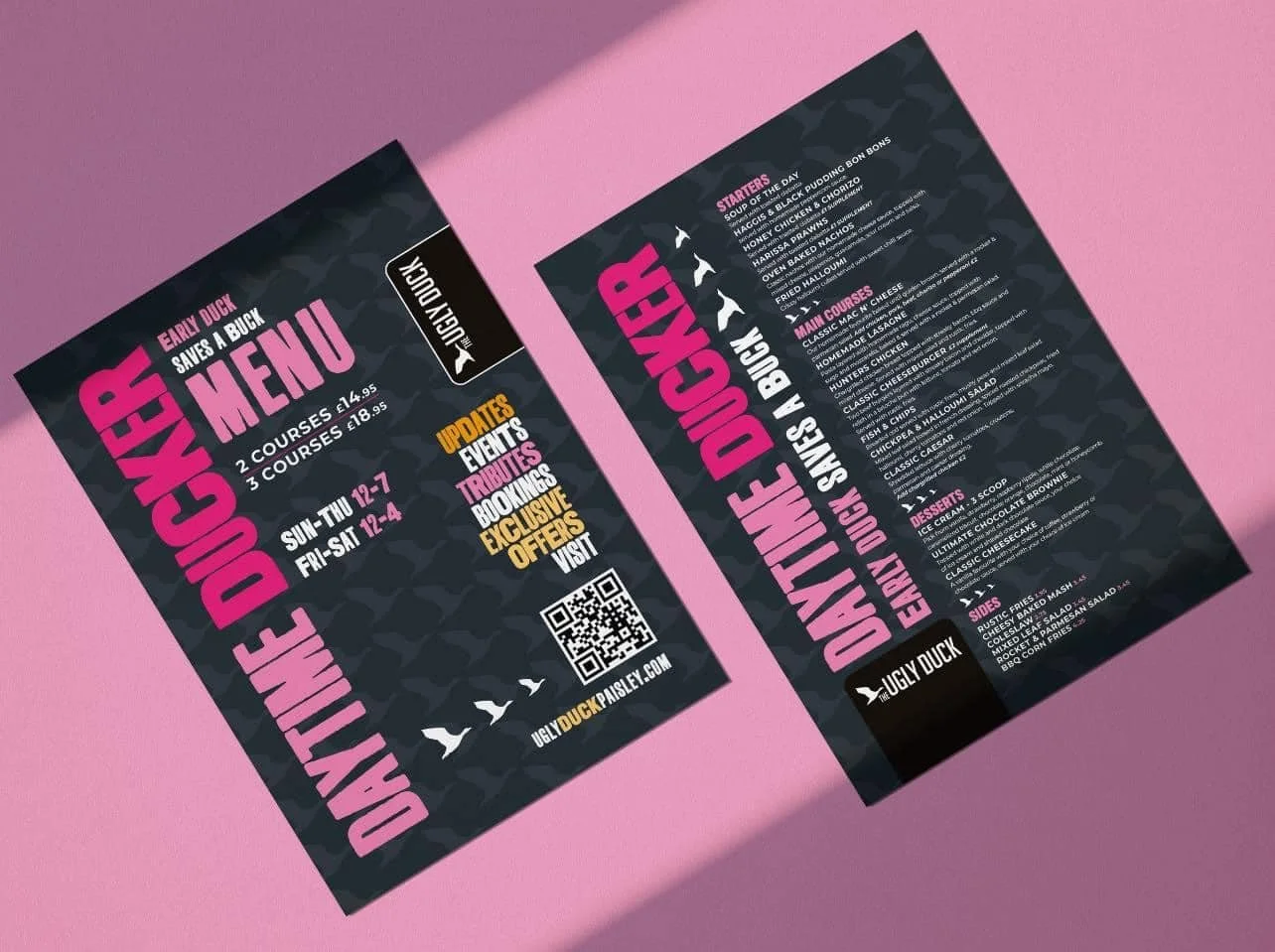 Two black and pink flyers for Ugly Duck restaurant menu laying on a pink surface. The flyers list menu items, offers, and contact details.