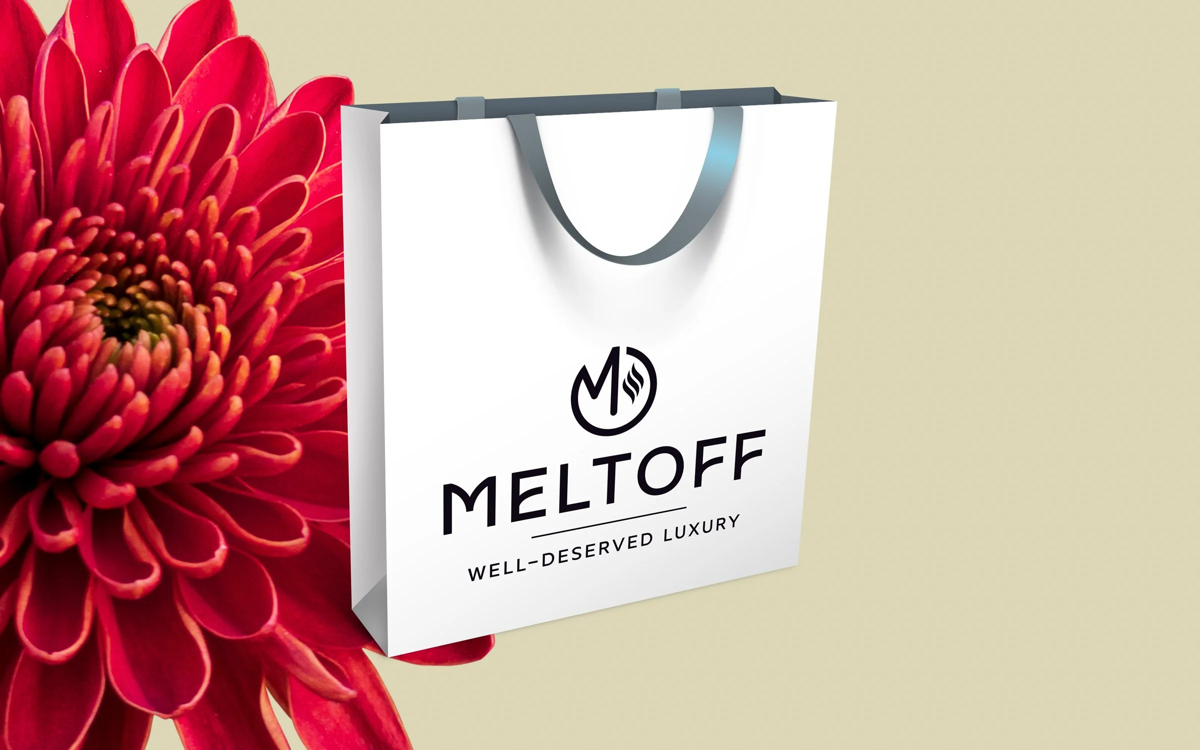 White Meltoff shopping bag with black handles, logo, and text, positioned next to a large red flower on a light yellow background.