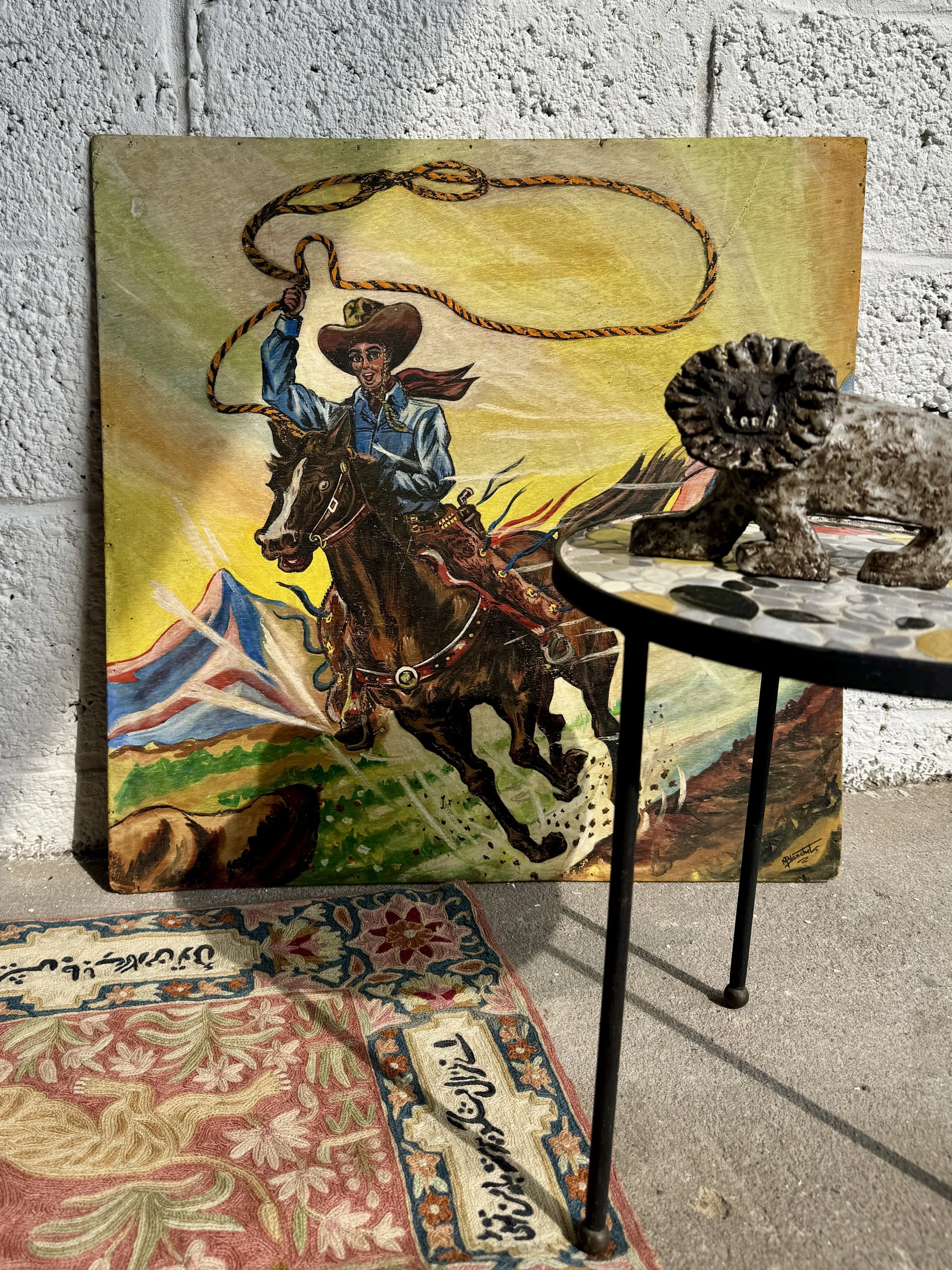 A colorful painting of a woman riding a horse while roping a calf, with mountains in the background.