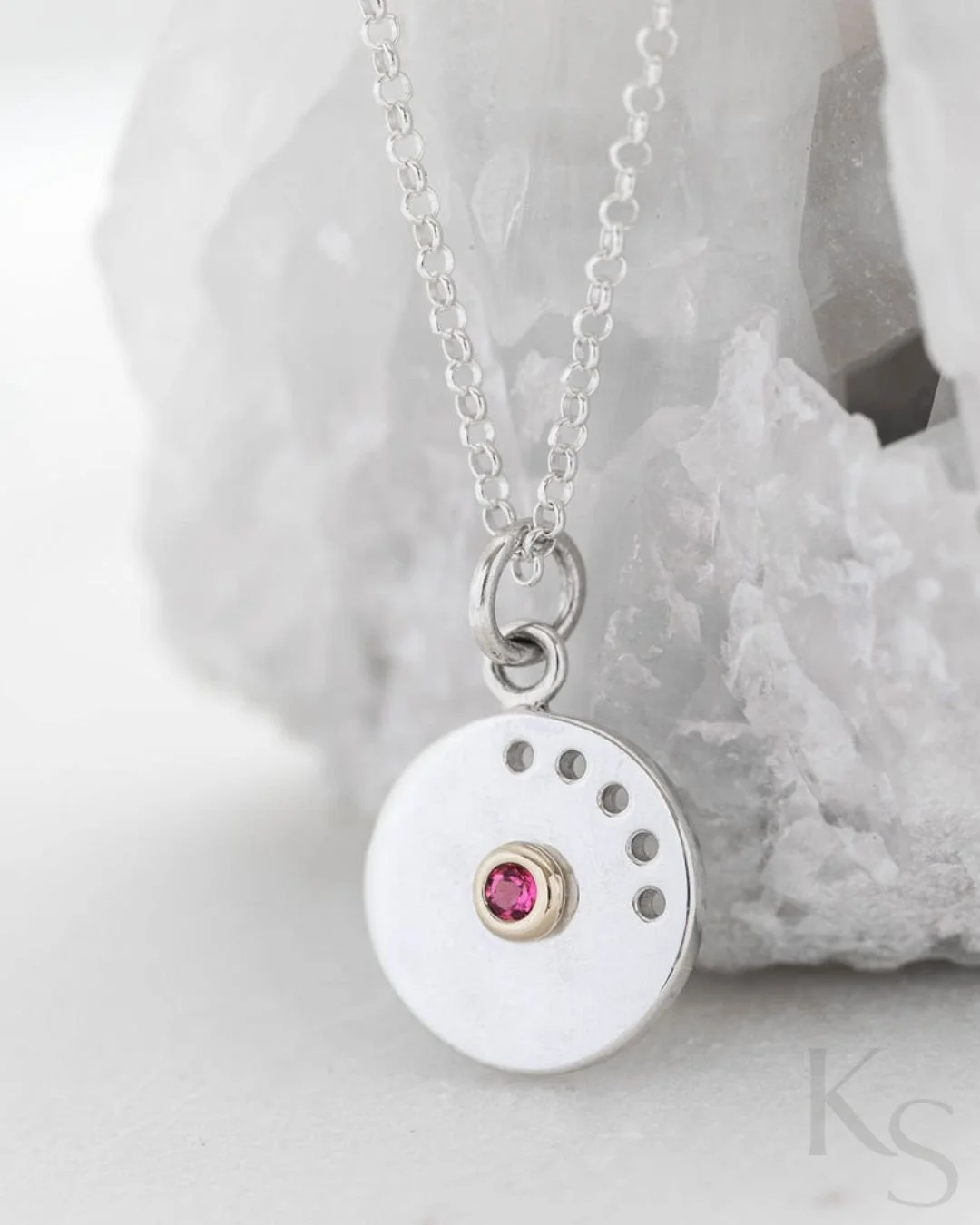 The Marguerite pink tourmaline pendant was inspired by the daisy - a study in botanical symmetry and clean, minimalist lines.

This piece features a 12mm sterling silver disc with pierced detailing, polished to a high-shine mirror finish. At the cent
