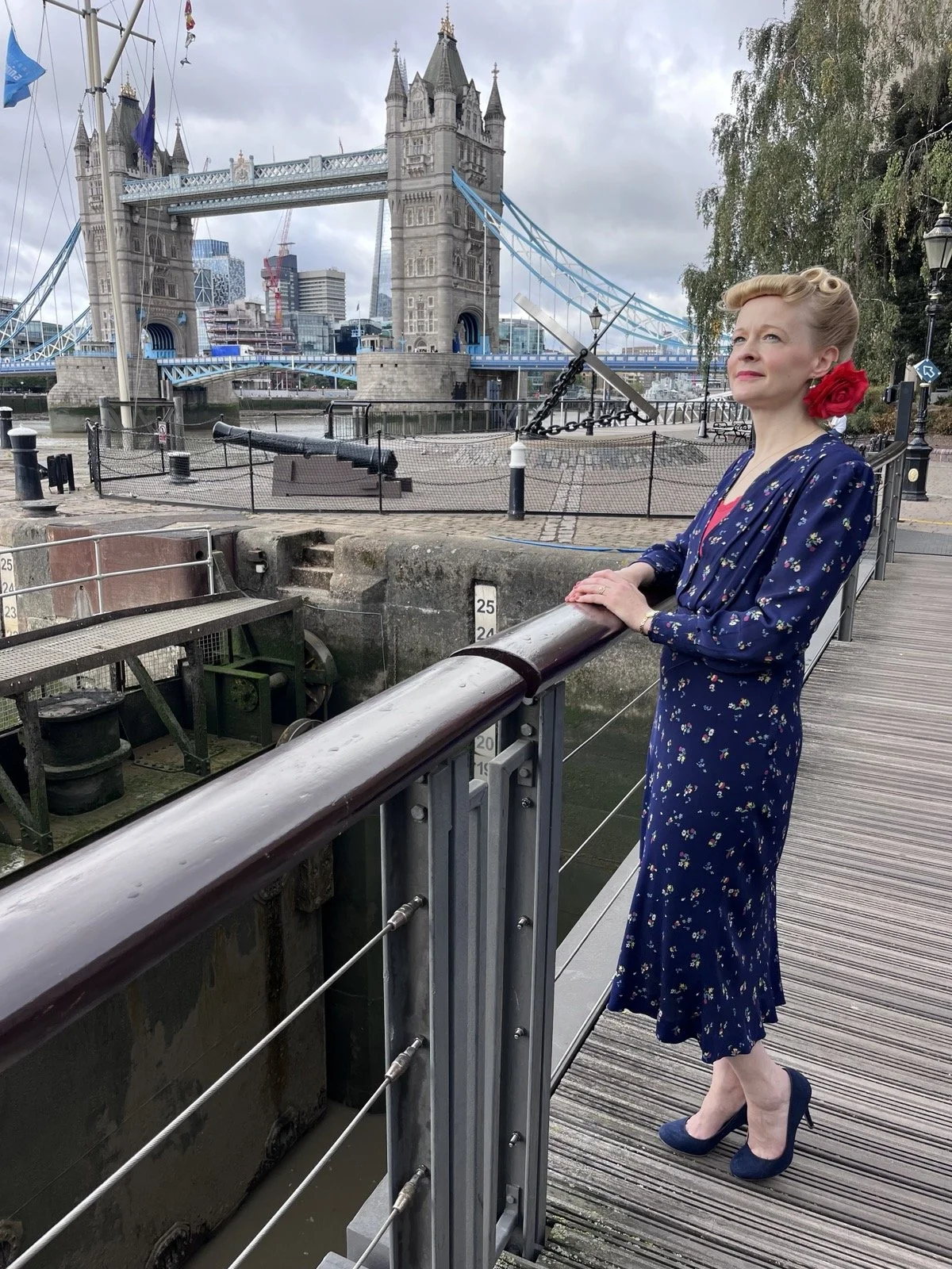 Kitty Mazinsky in vintage styling beside the Thames with Tower Bridge in the background, London.