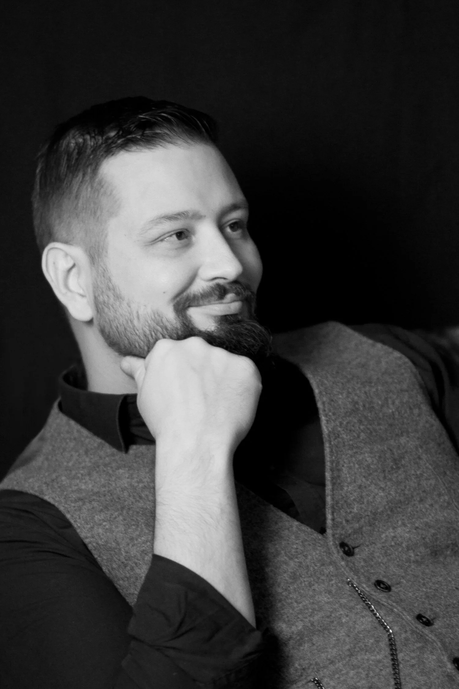 Schwarz-weiß-Porträt eines lächelnden Mannes mit Bart (Christoph Haidinger), nachdenklich mit der Hand am Kinn.