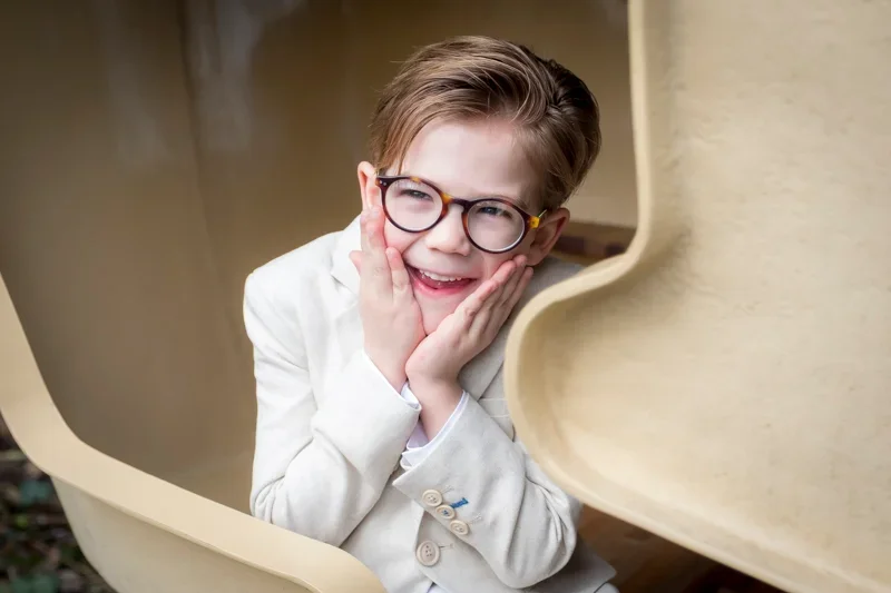 portret_45_jongen_communie_beige kostuum_bril_schattig_lach.webp
