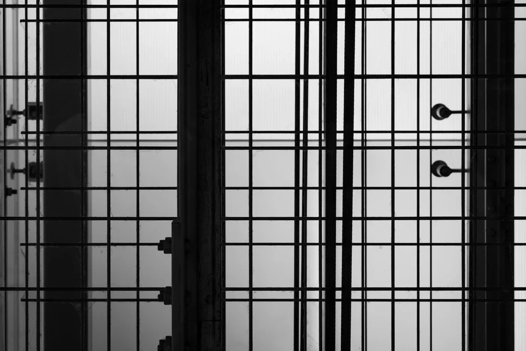 Close-up van een metalen werking met rasterpatroon, zwart-wit foto, mogelijk onderdeel van een kantoorgebouw of industrieel systeem.