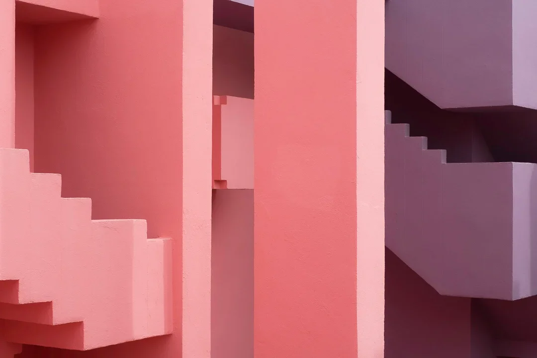 Close-up van een abstract geometrisch gebouw met roze en paarse kleurvlakken en trappen.