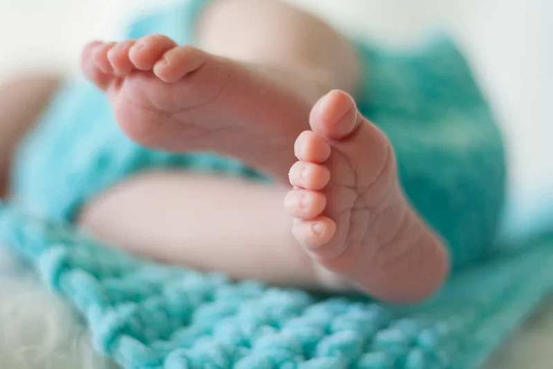 Close-up van babyvoetjes in een turquoise deken.