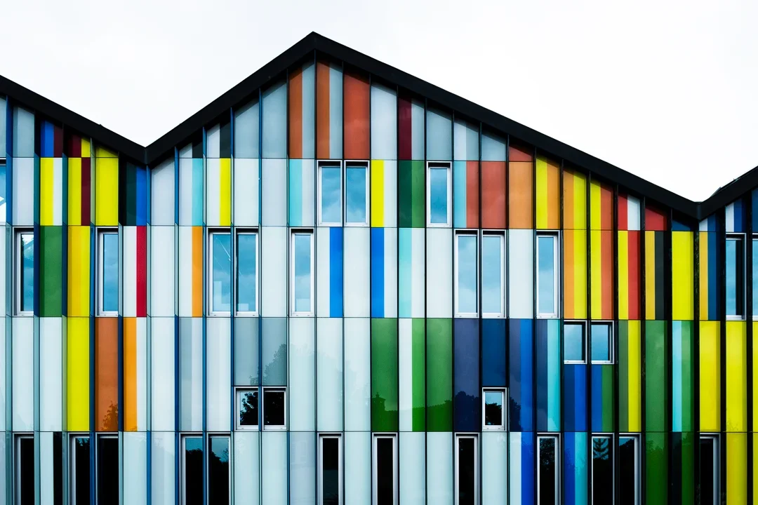 Moderne gevel van een gebouw met kleurrijke verticale panelen en ramen.