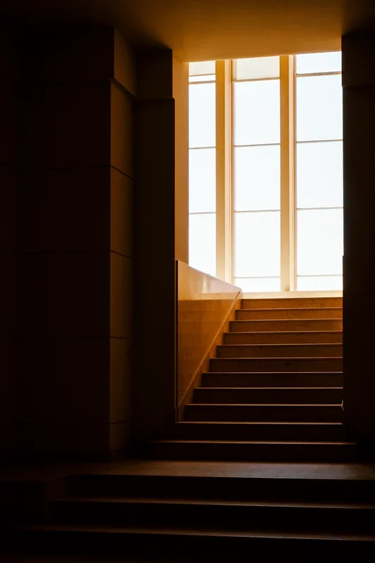 Trap naar een bovenverdieping met grote ramen die zonlicht binnenlaten.