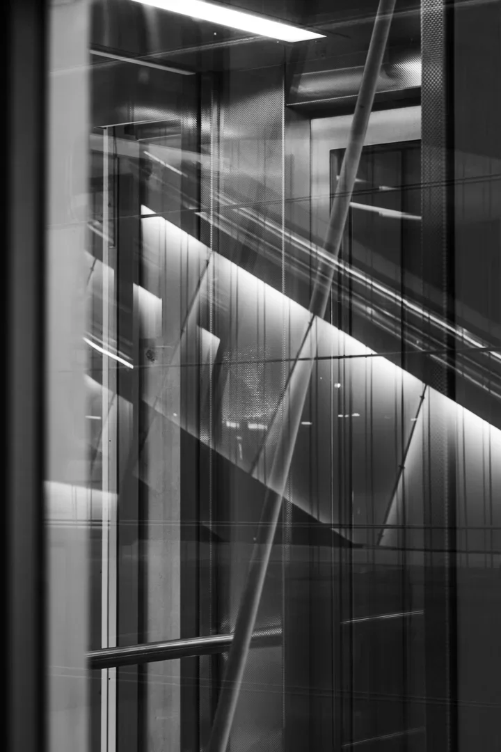 Interieur van een modern gebouw met glazen muren, ijzeren balken en trappen.