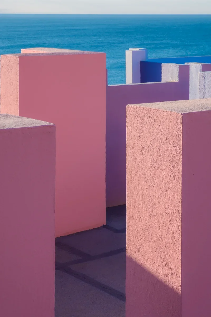 Zweefmuurkunst in pastelroze, paarse en blauwe kleuren met uitzicht op zee op de achtergrond.