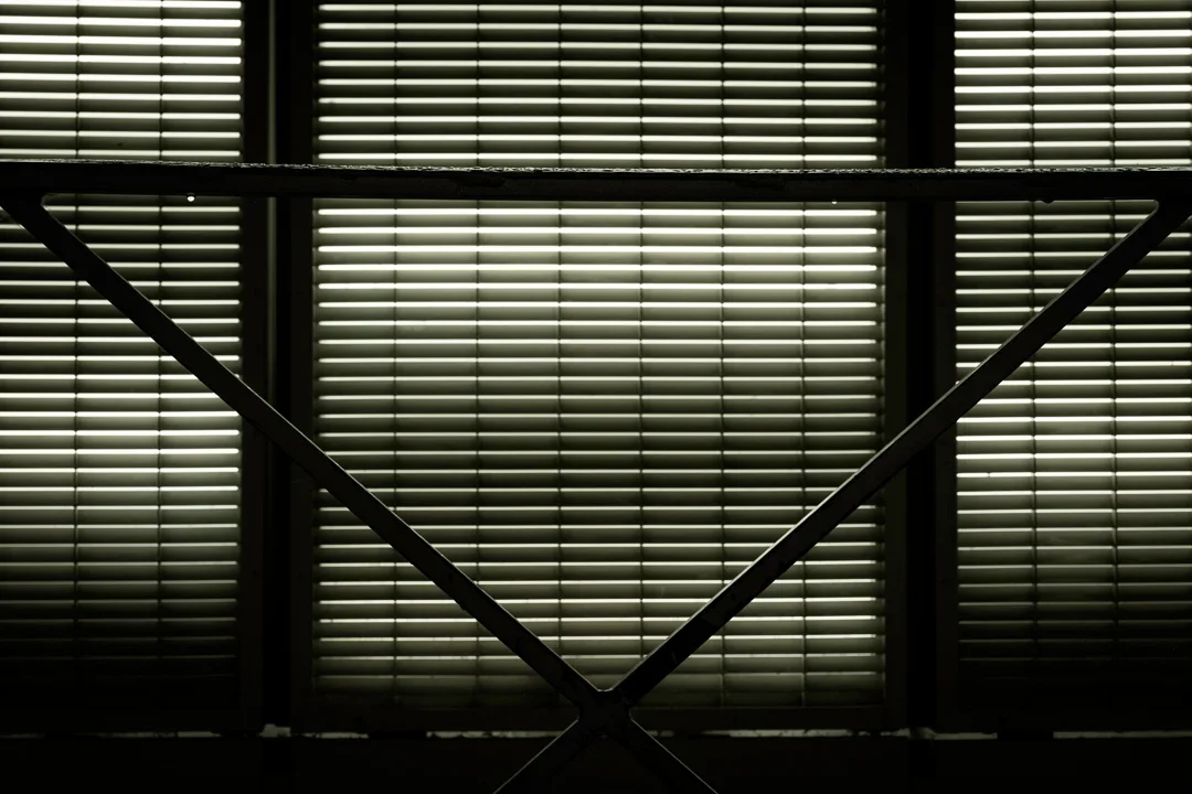 Een silhouet van een treinbackup met een achtergrond van gesloten horizontale jaloezieën die licht binnenlaten.