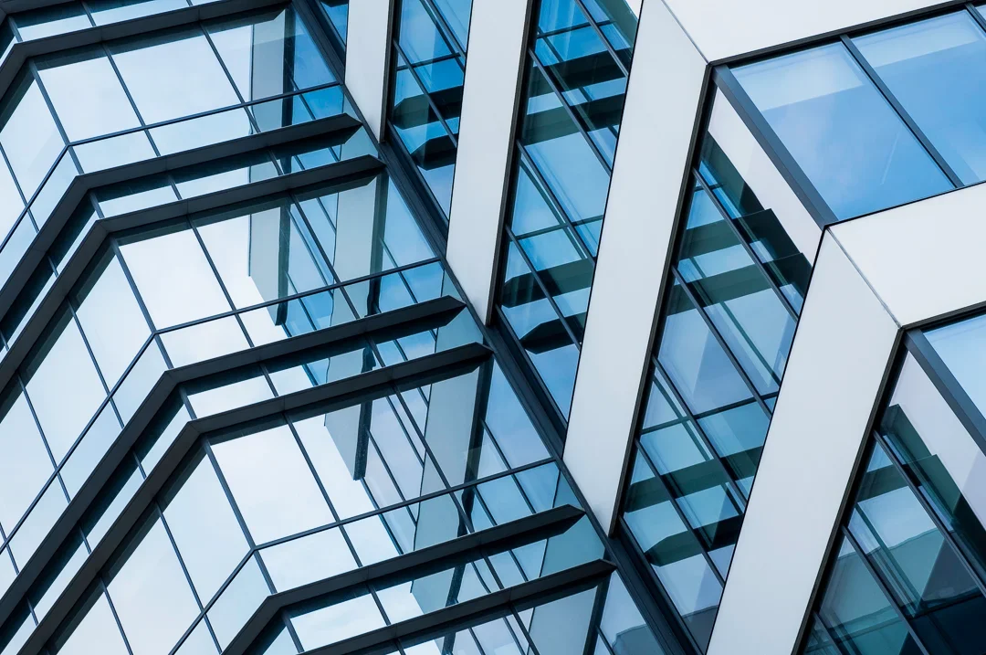 Close-up van een modern kantoorgebouw met veel glazen ramen en geometrische vormen.