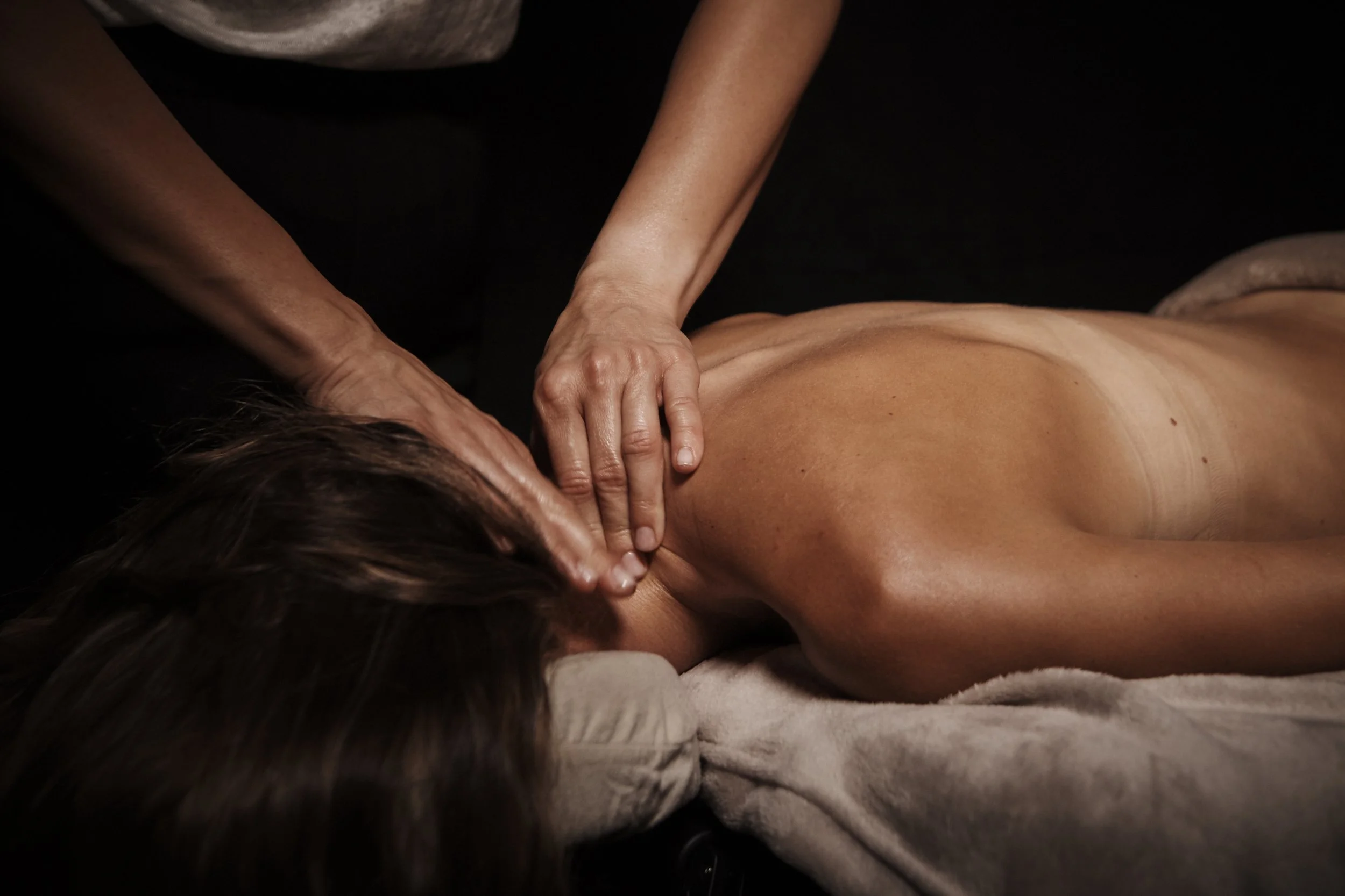 Person receiving a massage on their back in a dark environment.