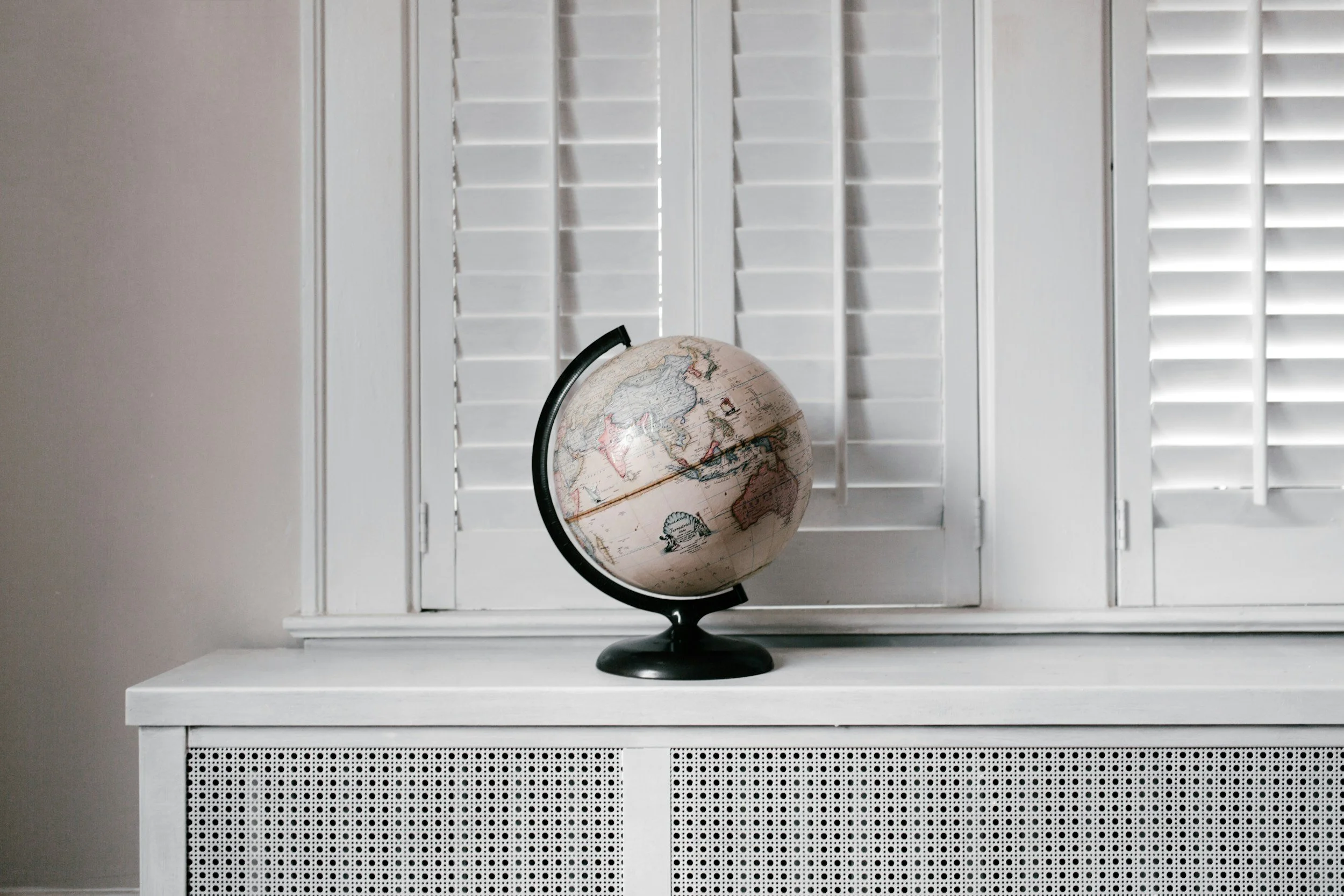 A globe placed on a white table in front of white window shutters in Prescott, Arizona.