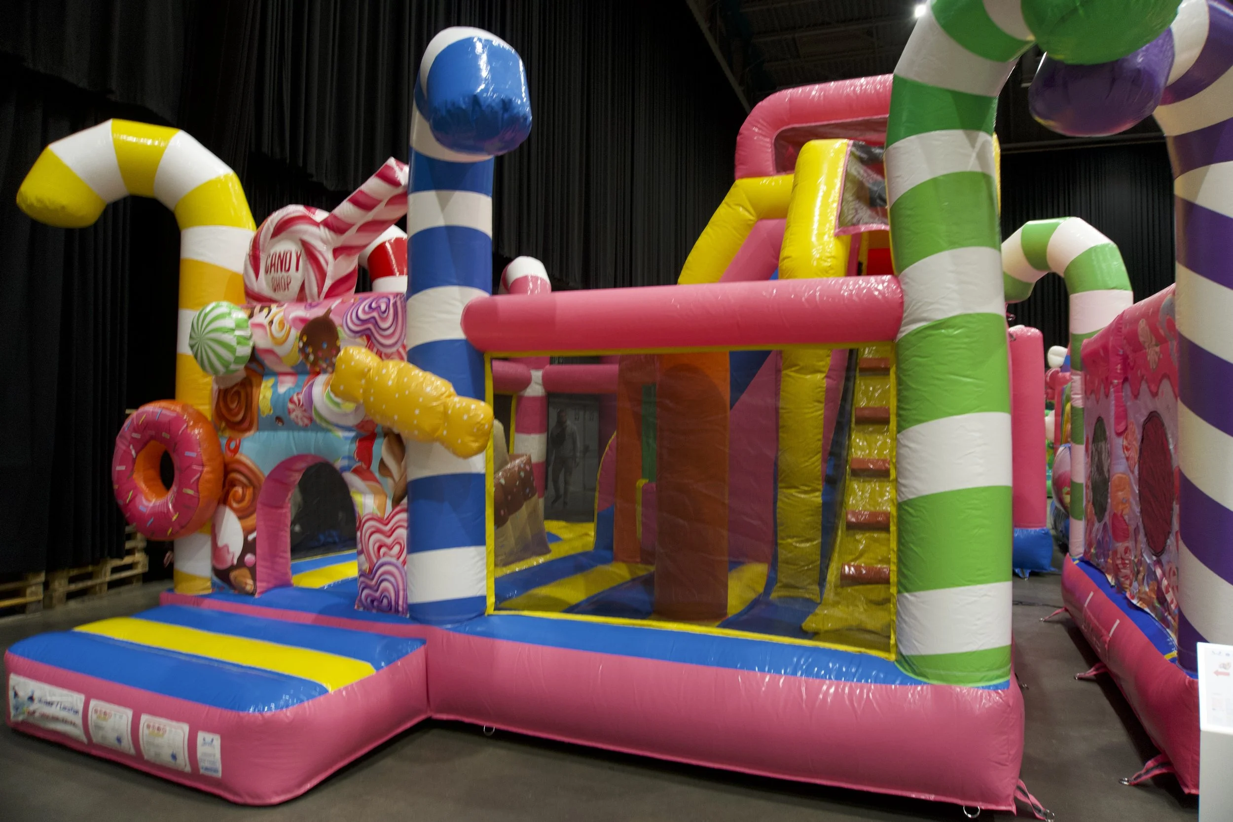 Colorrijk speeltoestel met candy-smaak thema, opvallend met roze, geel, blauw, groen en wit gebladerde pijpen, en diverse snoepvormige elementen.