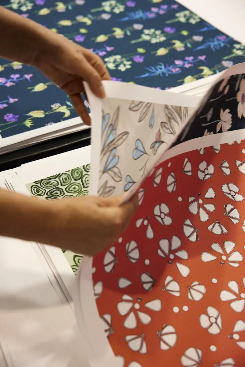 Designer's hand presenting original creations at textile fair.