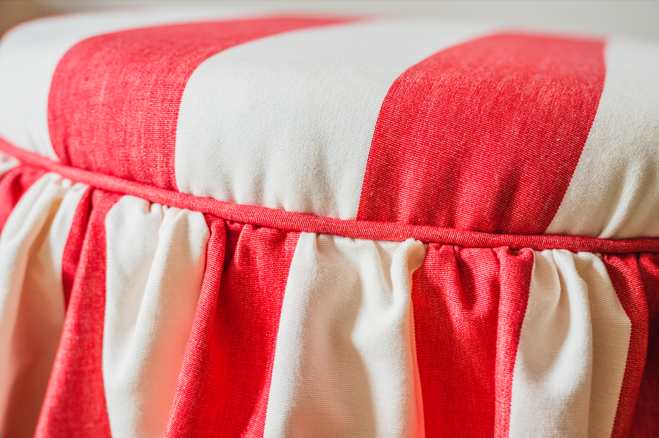 Close-up of a fabric with wide red and white vertical stripes and a gathered elastic waistband.