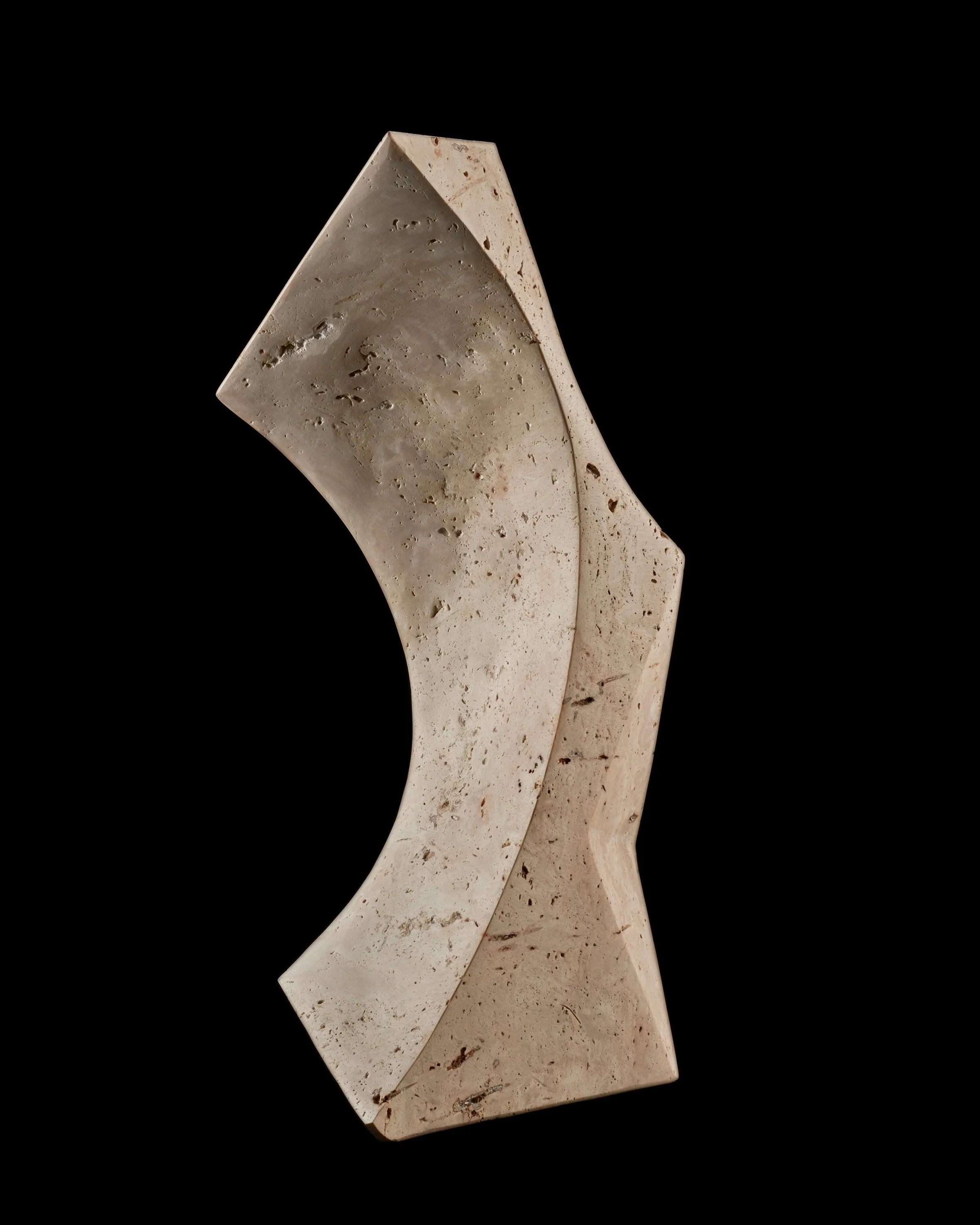 A modern, abstract sculpture made of light-colored stone with a smooth, curved shape and geometric angles, set against a black background.